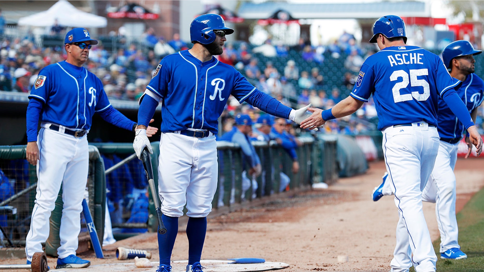 Kansas City Royals' Cody Asche (25) is greeted by teammate Tyler Collins, center, after scoring a run during the fifth inning of a spring training baseball game against the Cincinnati Reds, Wednesday, Feb. 28, 2018, in Surprise, Ariz.