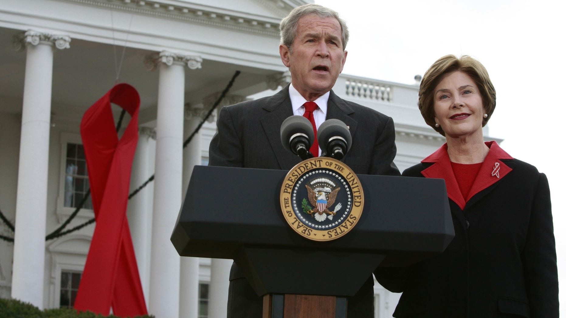 FILE -- Former President George W. Bush speaks alongside a giant red AIDS ribbon on the occasion of World AIDS day with first lady Laura Bush on the North Lawn of the White House in Washington December 1, 2008.
