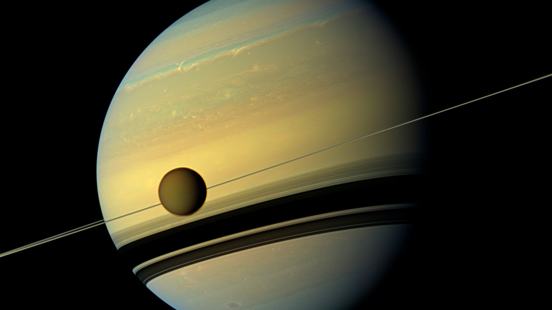 Titan, Saturn's largest moon appears before the planet as it undergoes seasonal changes in this natural color view from NASA's Cassini spacecraft in this handout released by NASA August 29, 2012.