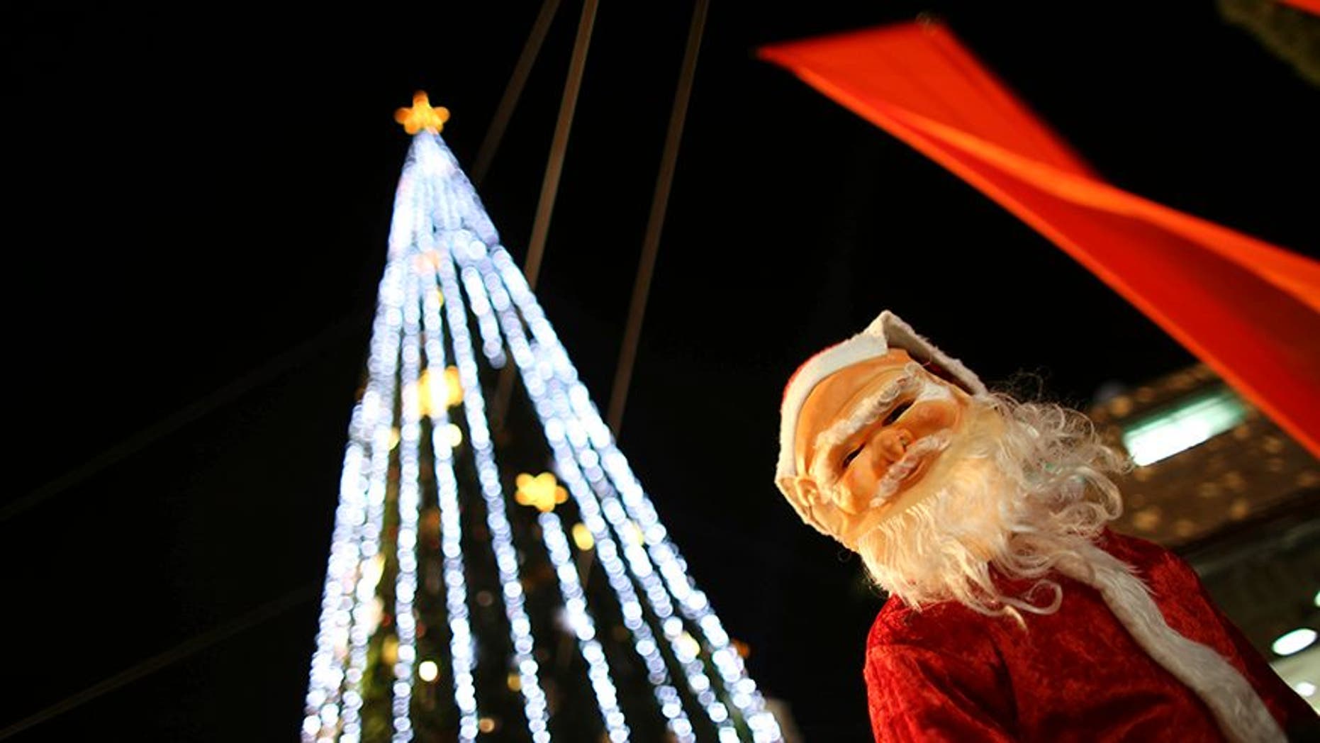 A boy wearing a Santa Claus costume attends a Christmas tree lighting ceremony in the northern town of Nazareth, the town of Jesus' boyhood, December 12, 2012. REUTERS/Ammar Awad (ISRAEL - Tags: RELIGION) - GM1E8CD0CSI01