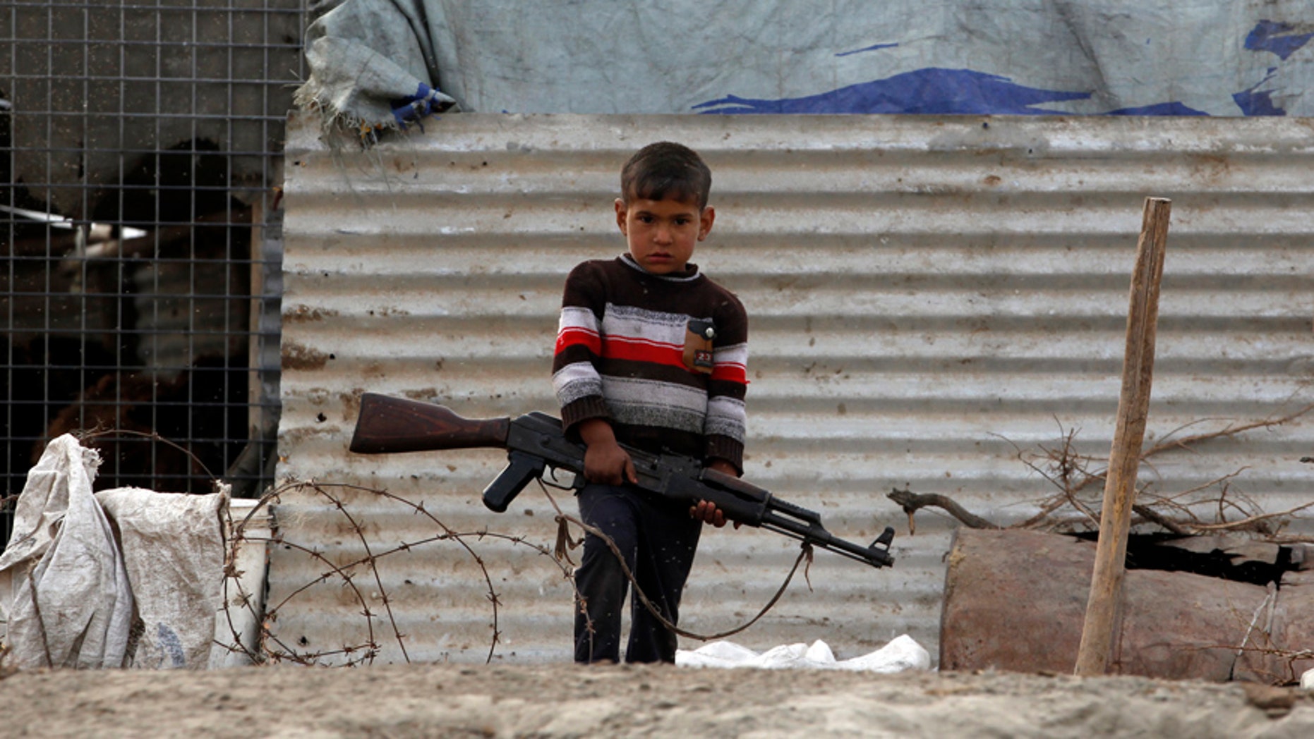 A boy carries a AK47 rifle at the Chebayesh marsh in Nassiriya, 300 km (185 miles) southeast of Baghdad, February 15, 2013. The Marsh Arabs who had farmed this area for thousands of years, were badly affected by a campaign mounted by the government of Saddam Hussein in the 1990s to destroy their lifestyle. The marshes were drained of water, and hundreds of thousands of Marsh Arabs were forced to flee to cities, where they live in poverty, the locals in this area said. Picture taken February 15. REUTERS/Thaier al-Sudani (IRAQ - Tags: SOCIETY TPX IMAGES OF THE DAY) - RTR3DV42