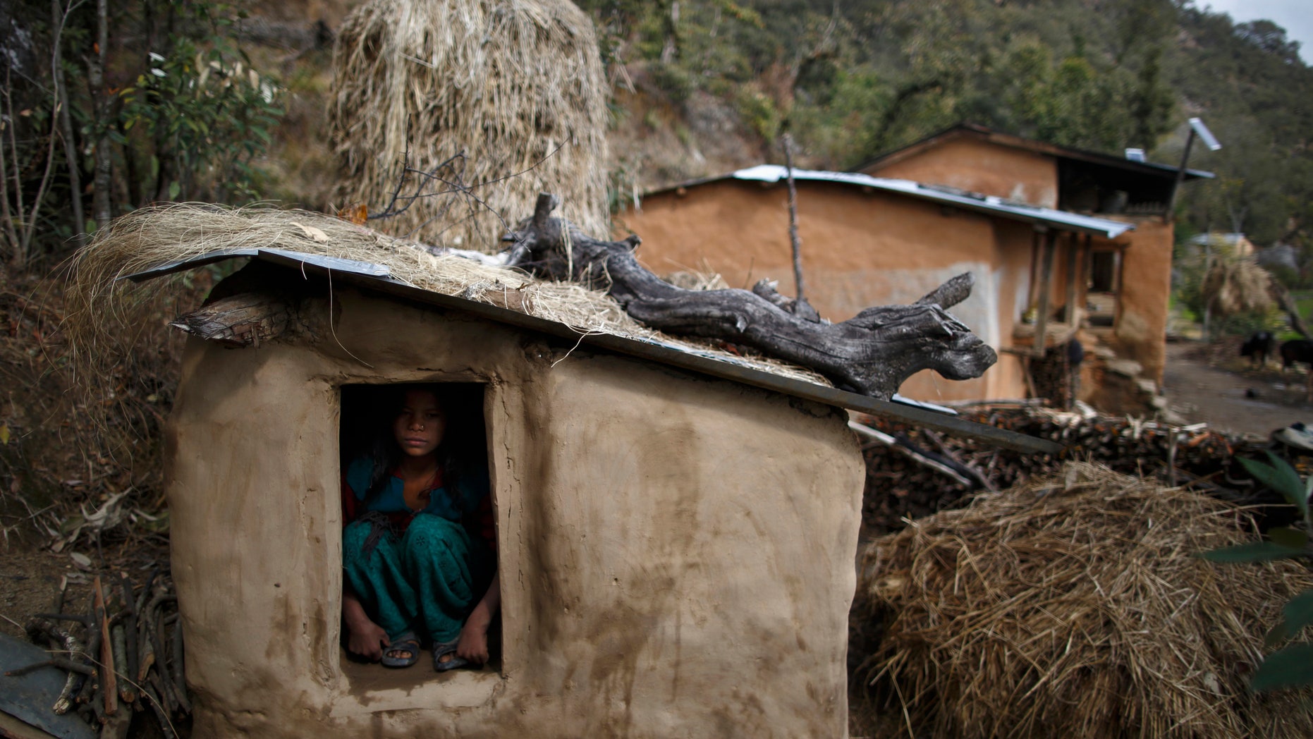 Uttara Saud, 14, sits inside a Chaupadi shed in the hills of Legudsen village in Achham District in western Nepal February 16, 2014