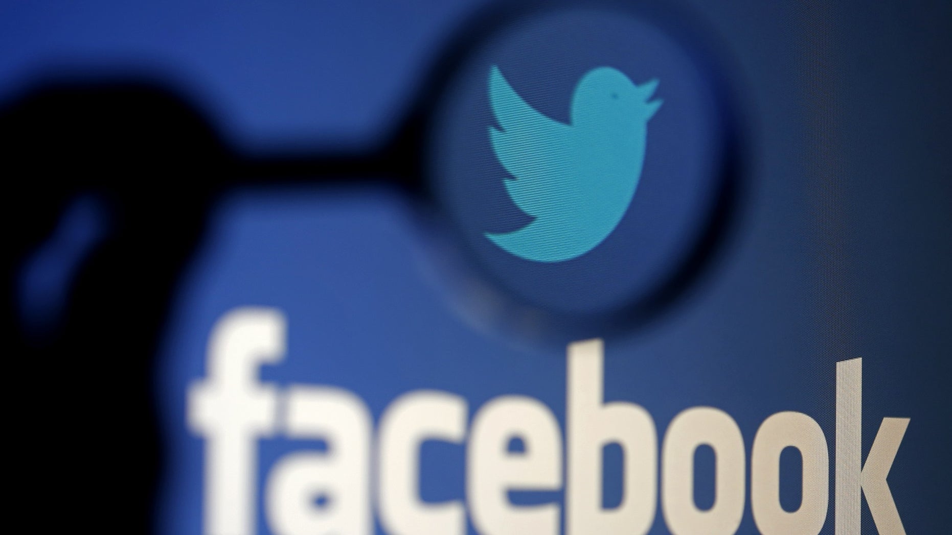 A logo of Twitter is pictured next to the logo of Facebook in this photo illustration.