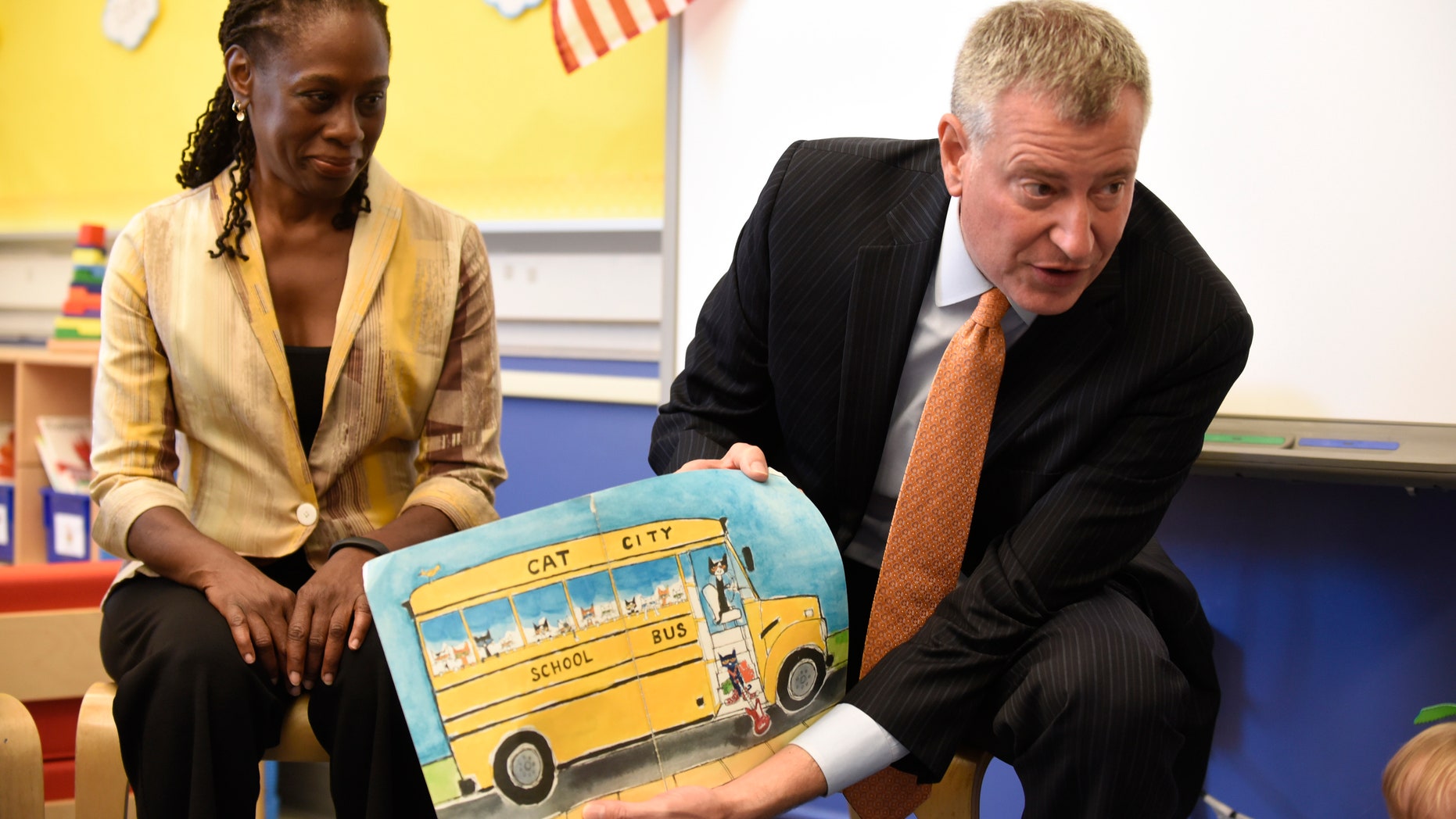 New York City Mayor Bill de Blasio (R) reads a book to pre-K students on their first day of school at Public School 59 in Staten Island, New York, September 9, 2015. At left is First Lady Chirlane McCray. REUTERS/Barry Williams/Pool
