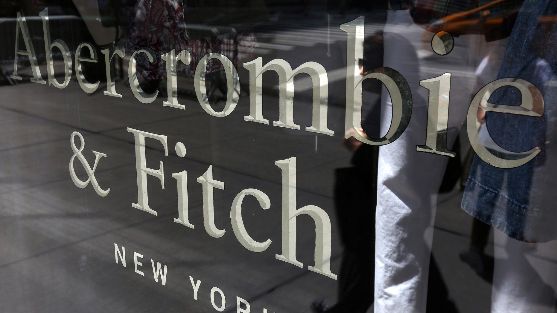 A woman is reflected in a window as she walks past an Abercrombie & Fitch store on 5th Avenue in the Manhattan borough of New York.