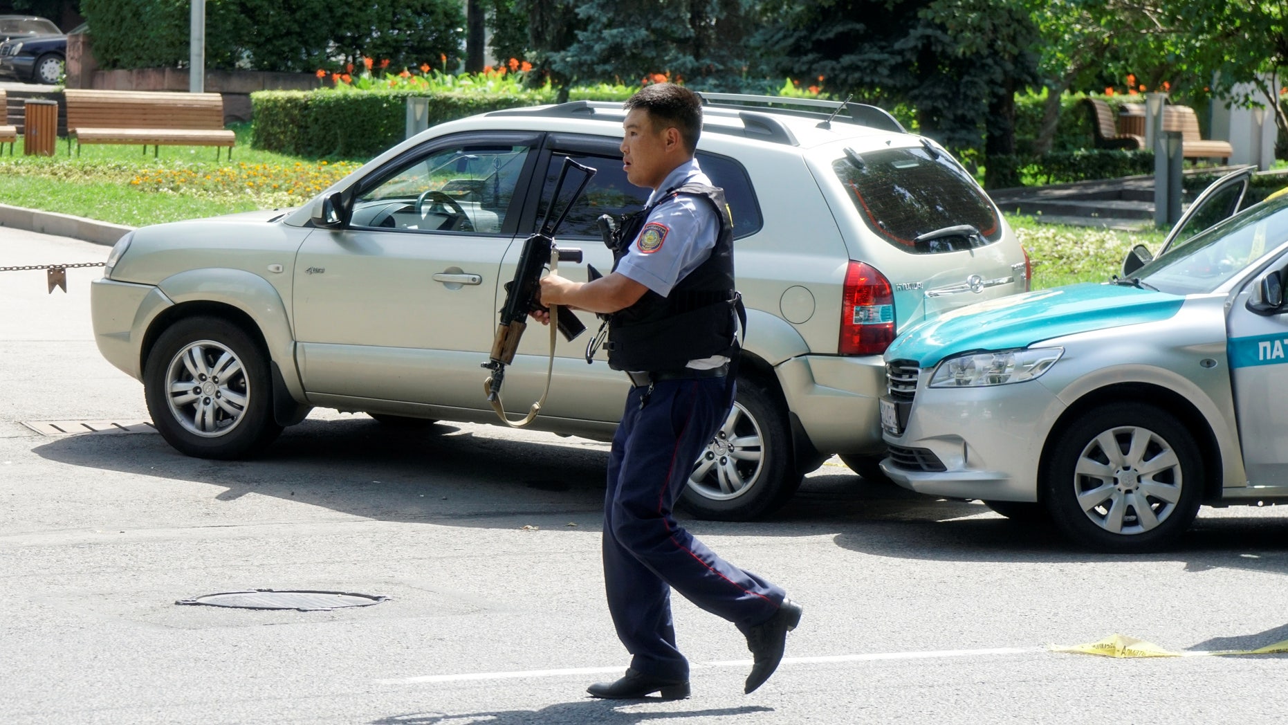 A policeman runs across the street in Almaty, Kazakhstan Monday.