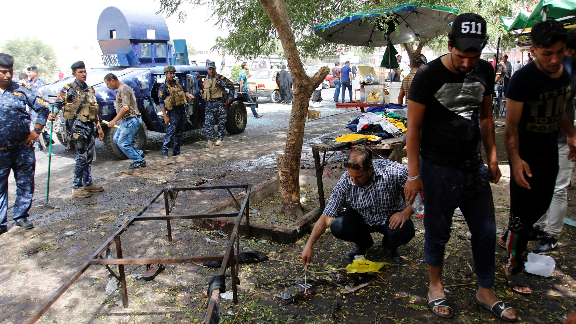 Residents and Iraqi security forces inspect the site where a suicide bomber detonated his explosive vest at the entrance to Kadhimiya, a mostly Shi'ite Muslim district in northwest Baghdad, Iraq July 24, 2016. REUTERS/Khalid al Mousily - RTSJDJ7