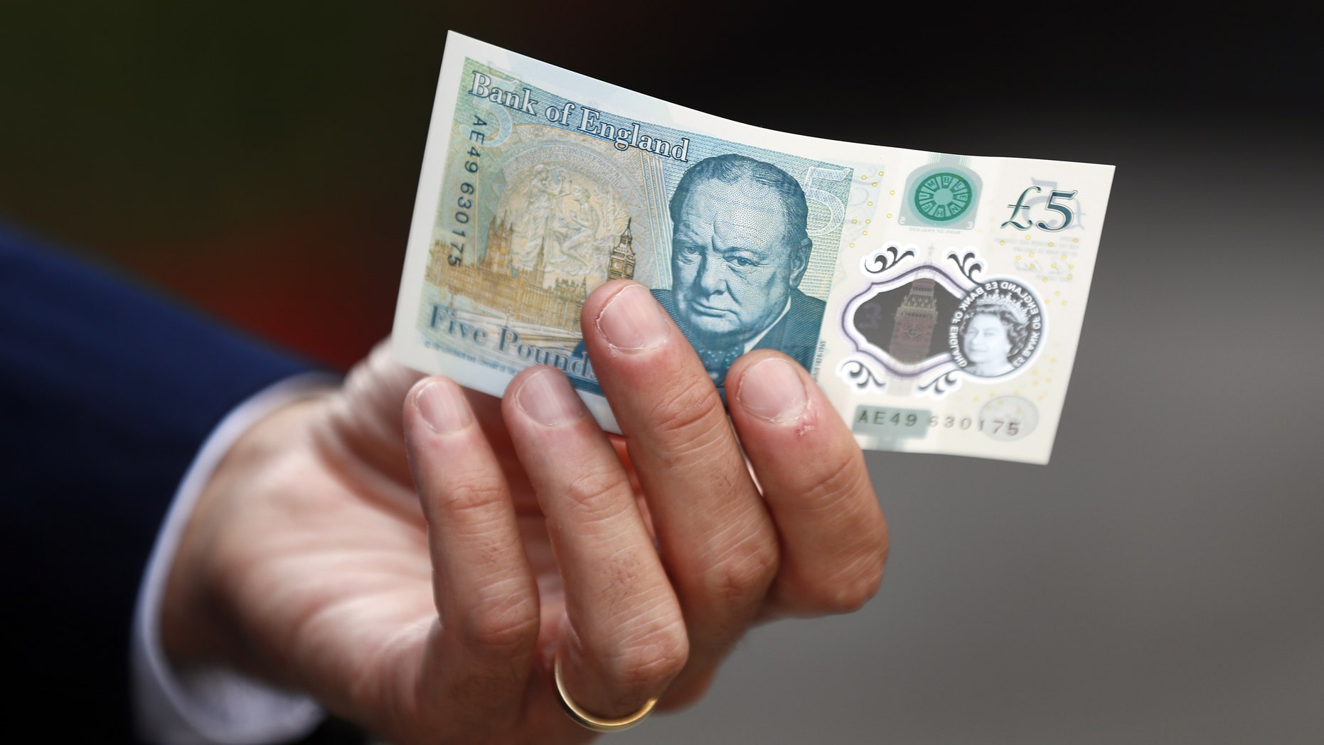 Bank of England governor Mark Carney poses with a new polymer five pound note at Whitecross Street Market in London, Britain September 13, 2016. (REUTERS/Stefan Wermuth)