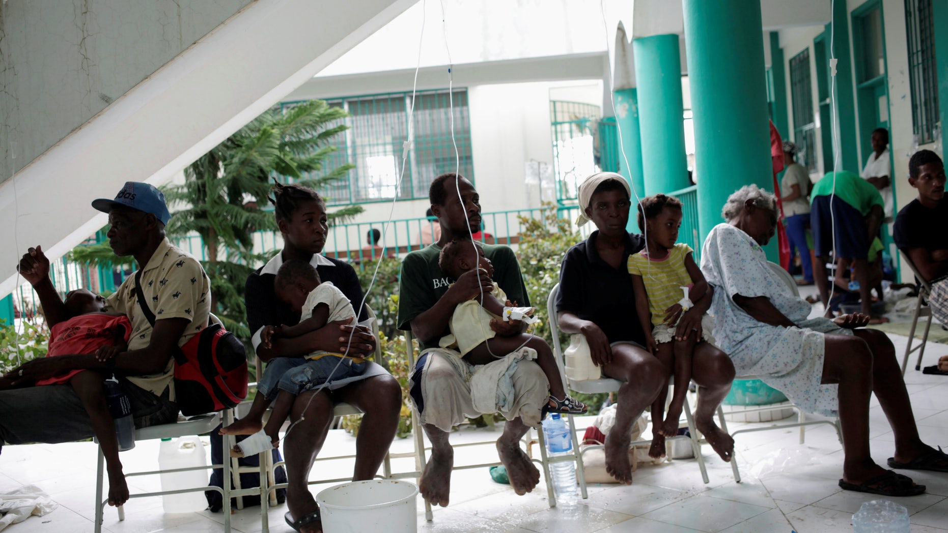 Adults hold children receiving treatment for cholera after Hurricane Matthew in the Hospital of Port-a-Piment, Haiti, October 9, 2016.