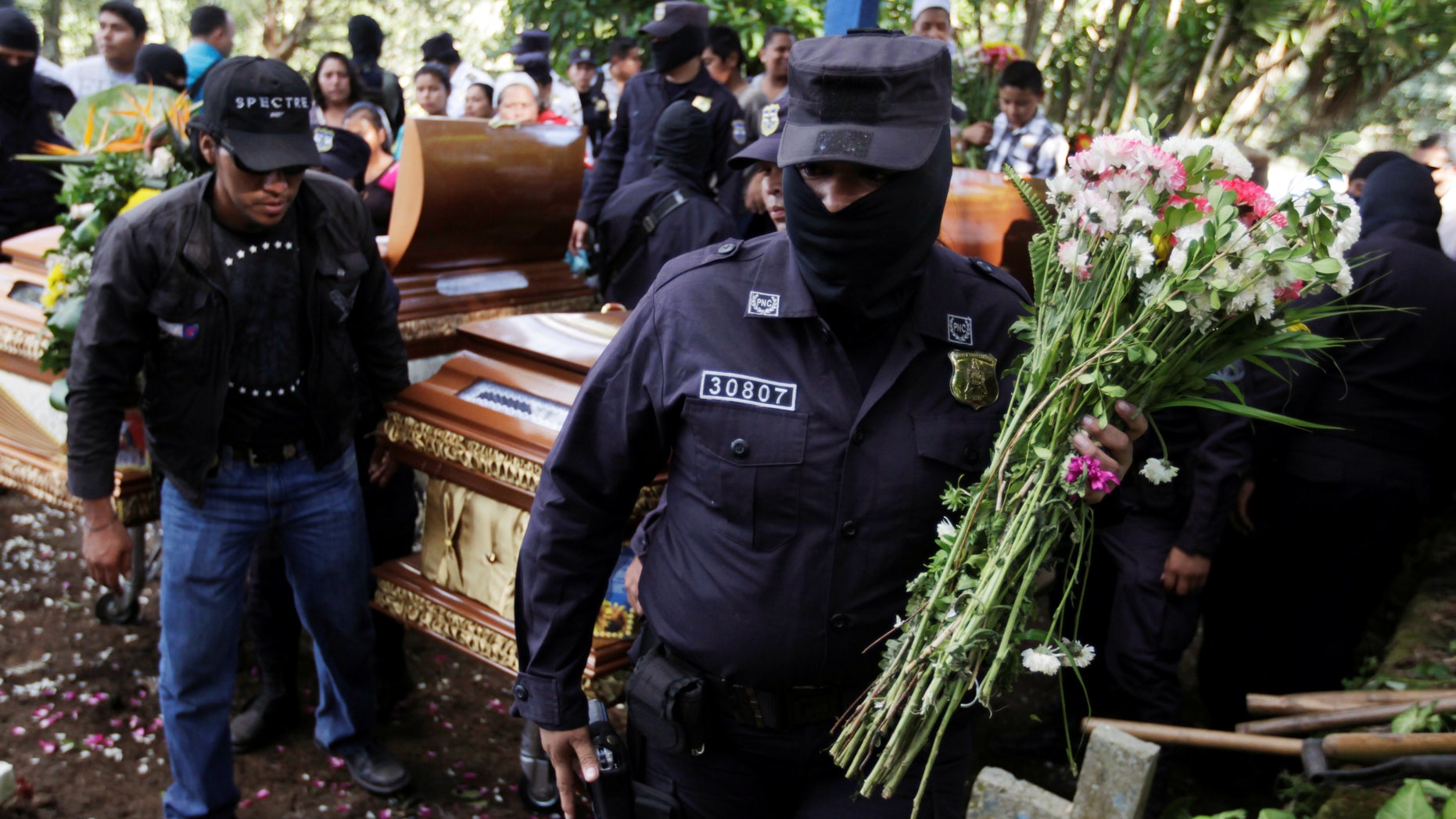 Salvadoran police officers participate in the funeral ceremony for their colleague Lorenzo Rojas Herrera and his son Marvin, who were killed by suspected gang members.
