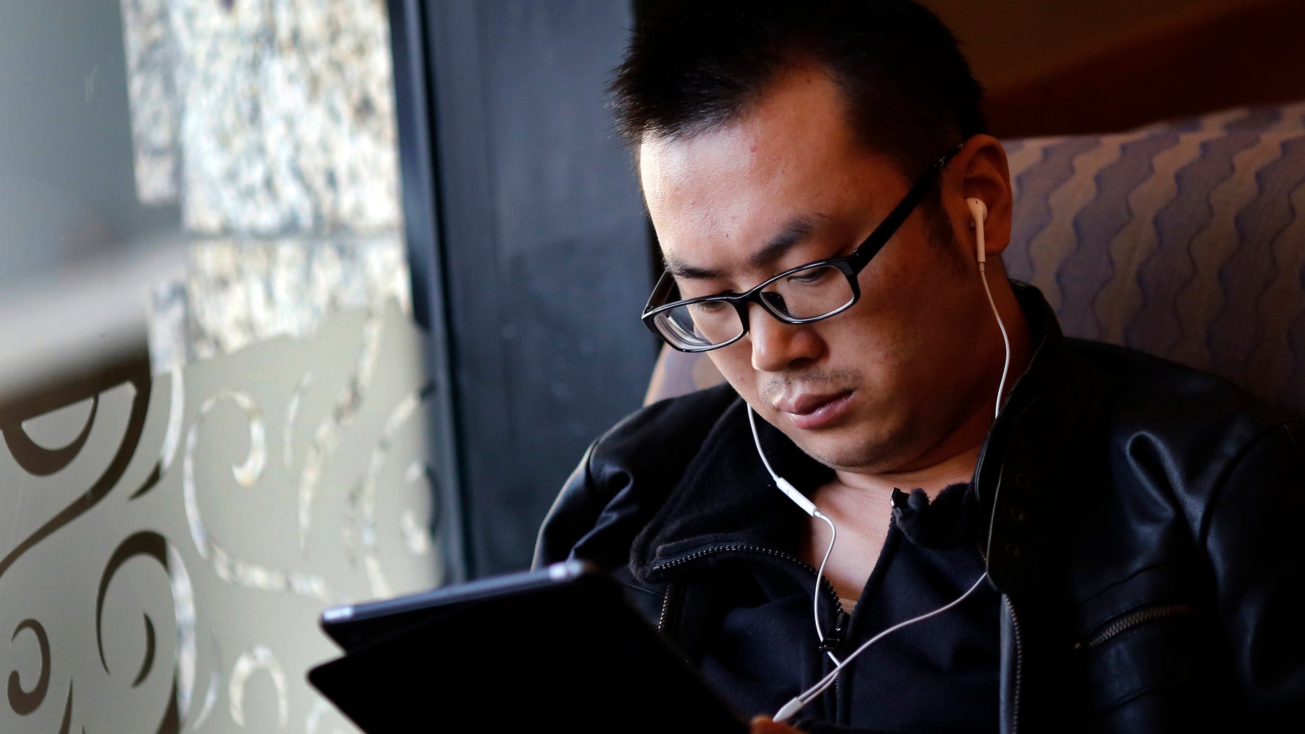 File photo. A man use his iPad inside a local coffee shop in downtown Shanghai November 28, 2013. (REUTERS/Carlos Barria)