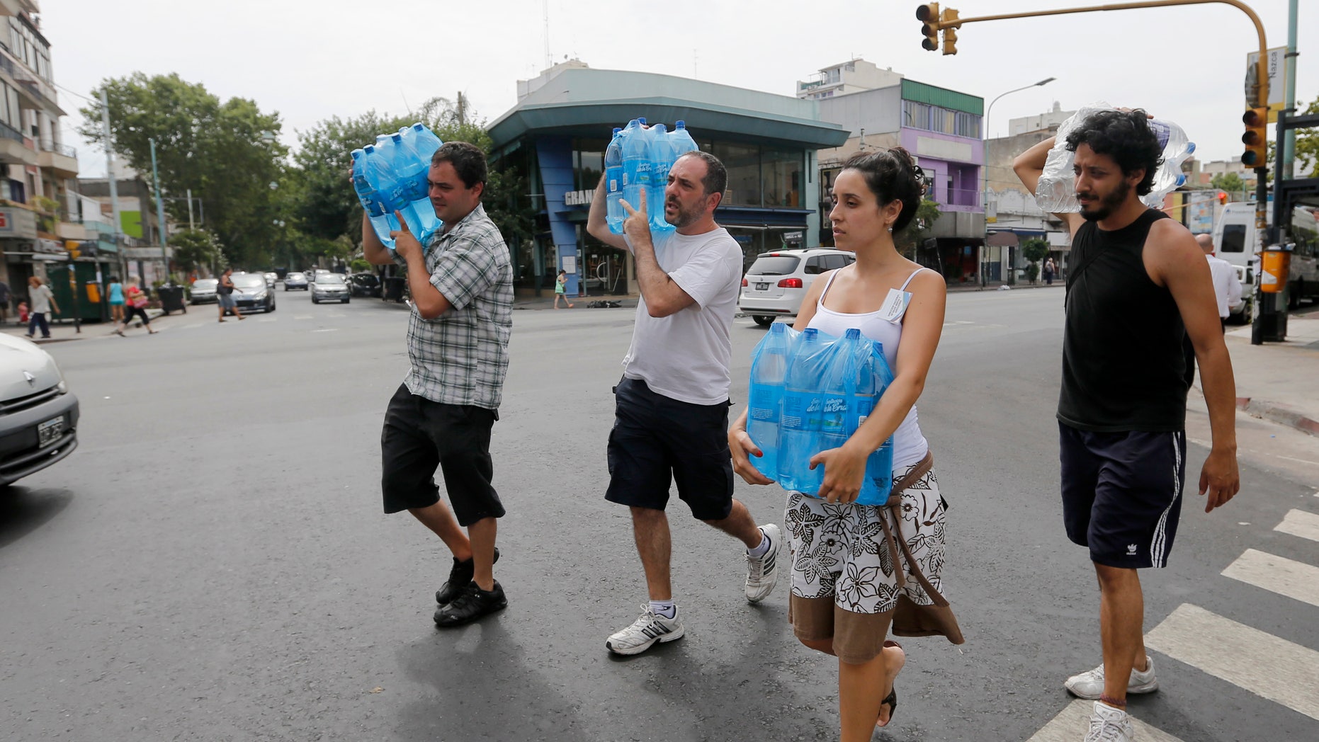 Residents carry packs of water during a heat wave that led to record electricity consumption in Buenos Aires December 30, 2013. With temperatures reaching 100 degrees, water and power outages blanket large swaths of Argentina's capital city, sparking protests and placing residents, particularly those in high-rise buildings, at risk. (REUTERS/Enrique Marcarian)