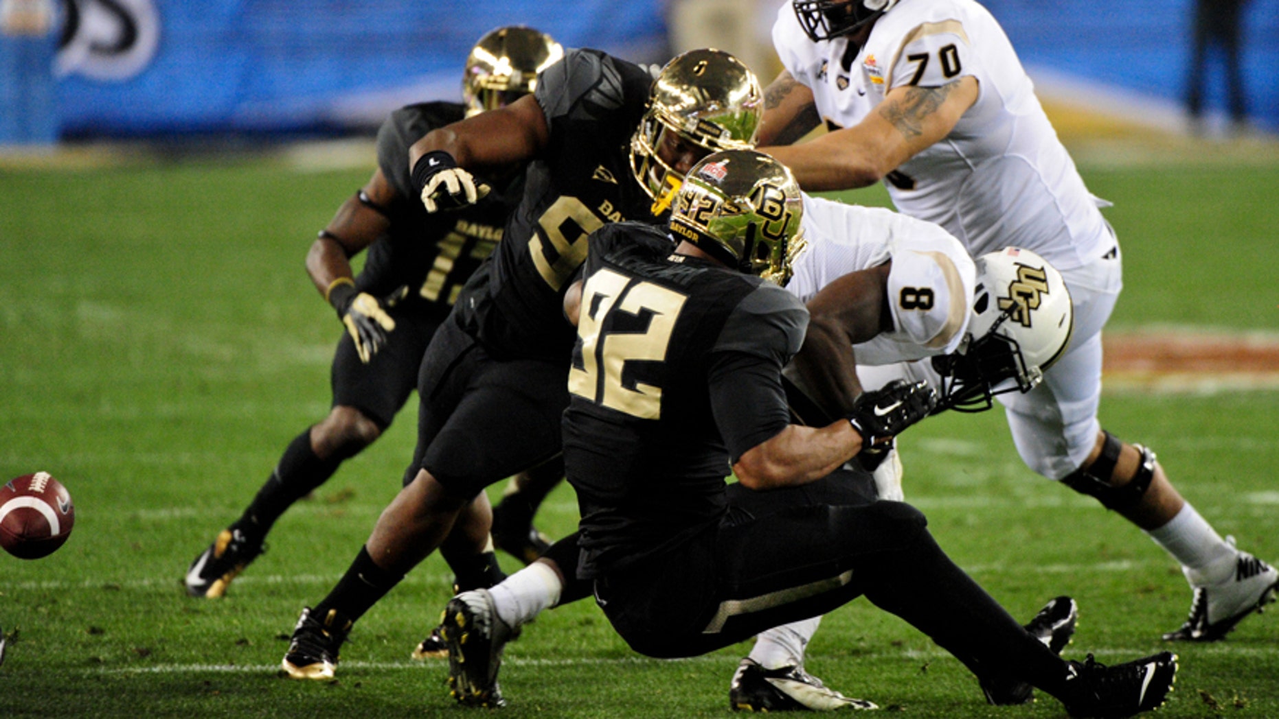 Jan 1, 2014; Glendale, AZ, USA; UCF Knights running back Storm Johnson (8) fumbles the ball while being tackled by Baylor Bears defensive lineman Byron Bonds (96) and defensive end Shawn Oakman (2) during the first half in the Fiesta Bowl at University of Phoenix Stadium. Mandatory Credit: Matt Kartozian-USA TODAY Sports - RTX16ZOV