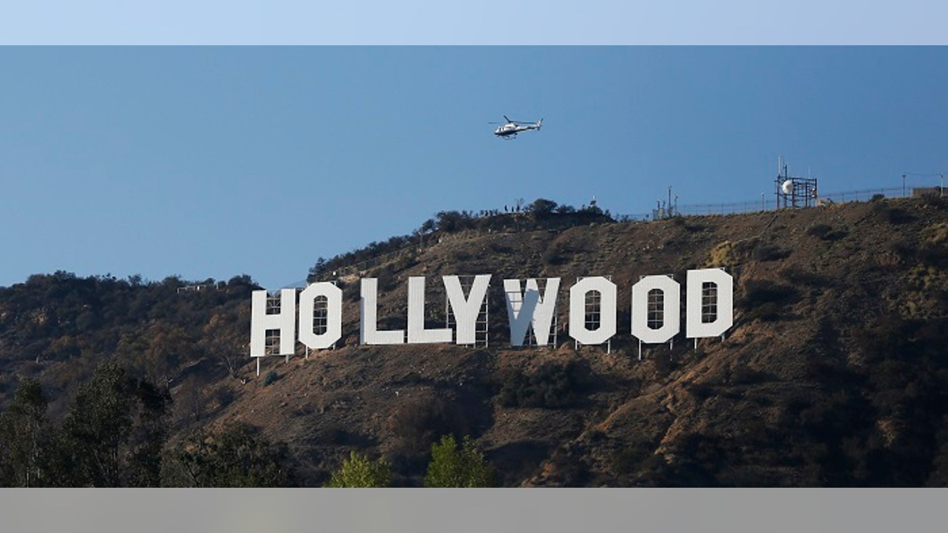 A Los Angeles Police Department (LAPD) helicopter flies over the Hollywood sign in Hollywood, California February 21, 2014. To match TRAVEL-HOLYWOOD REUTERS/Mario Anzuoni (UNITED STATES - Tags: ENTERTAINMENT ENVIRONMENT SOCIETY TRAVEL) - RTX19A0U