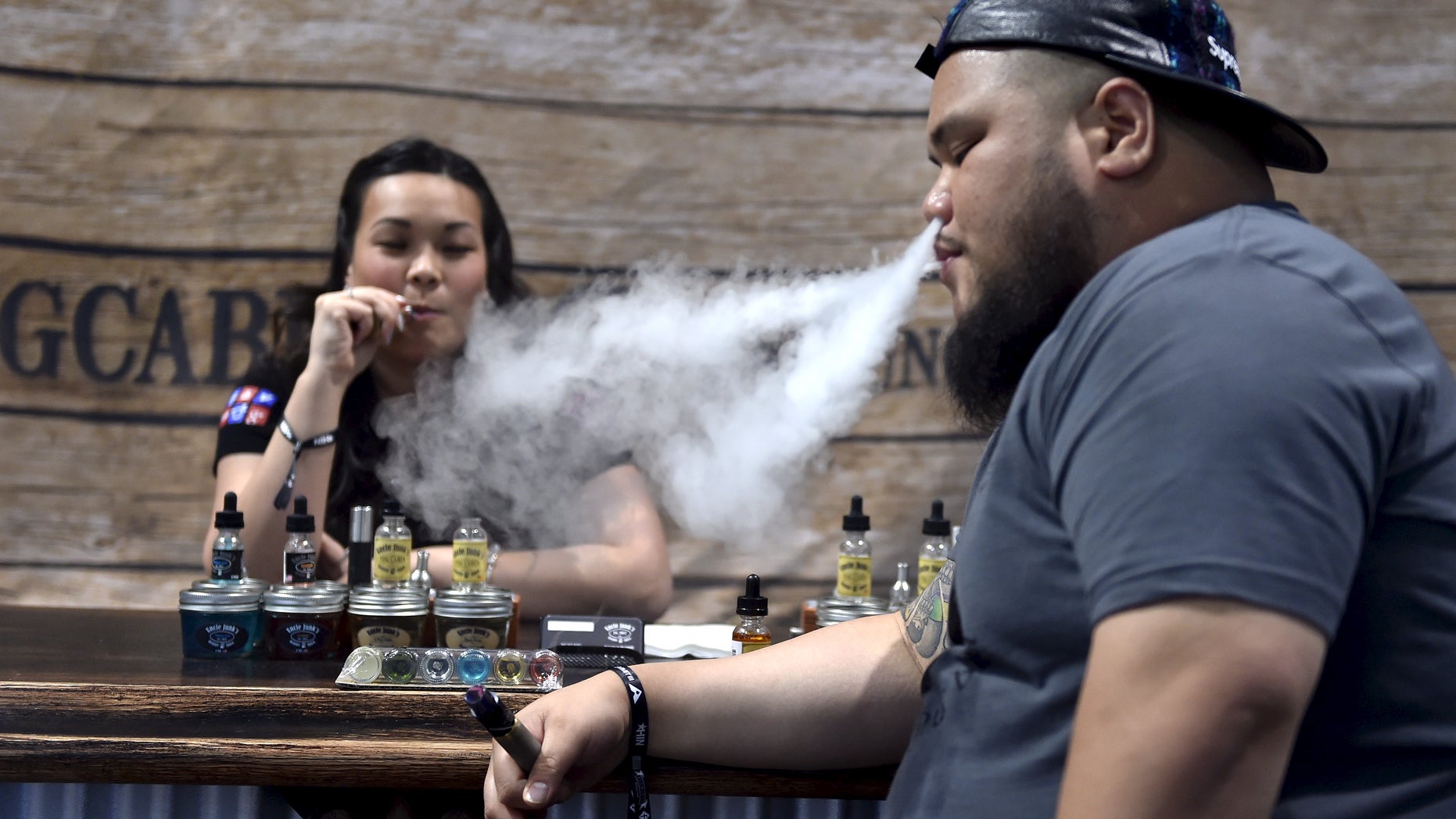 Annie Young (L) and Dan Leano smoke e-cigarette at the Vape Summit 3 in Las Vegas, Nevada May 2, 2015. According to new research provided to Reuters, youngsters say that the flavors of the vaping liquids, and the "ability to do tricks" are the top two reasons they consider electronic vaping devices cool. REUTERS/David Becker