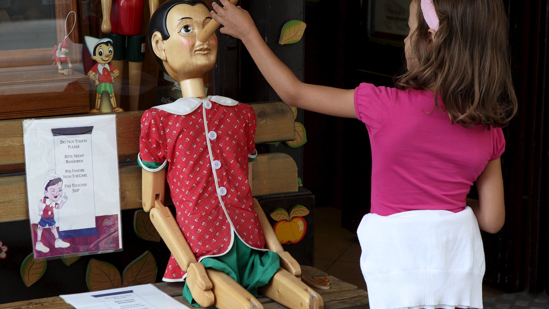 A child touches the nose of a Pinocchio puppet, a fictional character of a popular children's novel, at a woodwork souvenir shop in Vienna, Austria, August 21, 2015. (REUTERS/Heinz-Peter Bader)