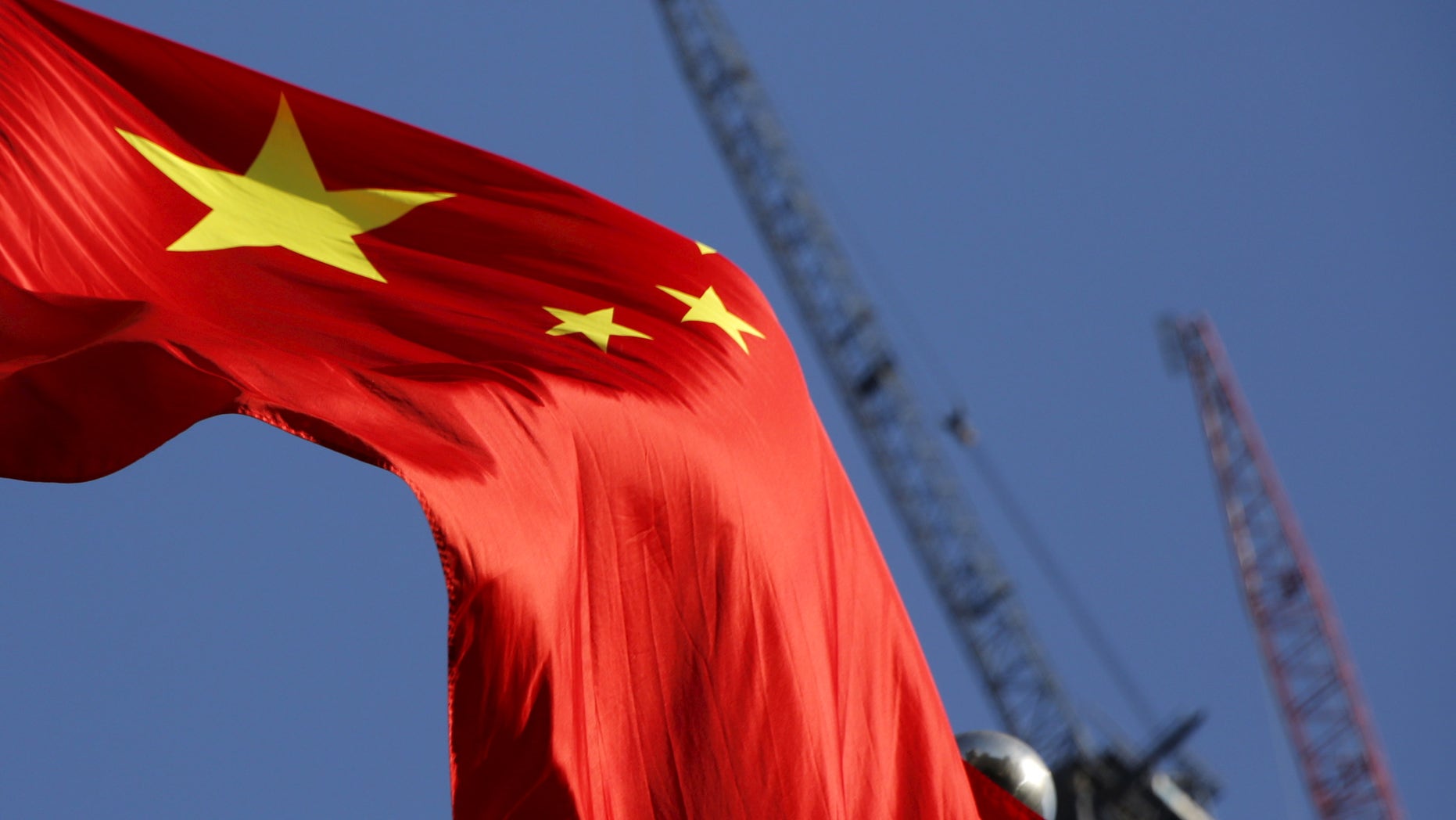 China's national flag is seen in front of cranes on a construction site at a commercial district in Beijing, China, January 26, 2016.
