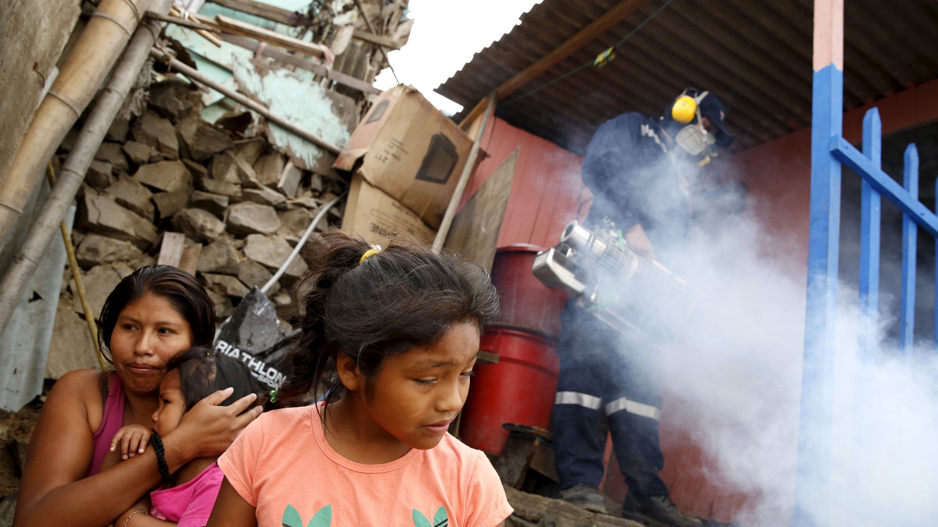 A health worker fumigates a house as residents wait outside during a campaign against the Zika virus and other mosquito-borne diseases at Carabayllo district on the outskirts of Lima, Peru February 1, 2016. REUTERS/Mariana Bazo - RTX24YRB