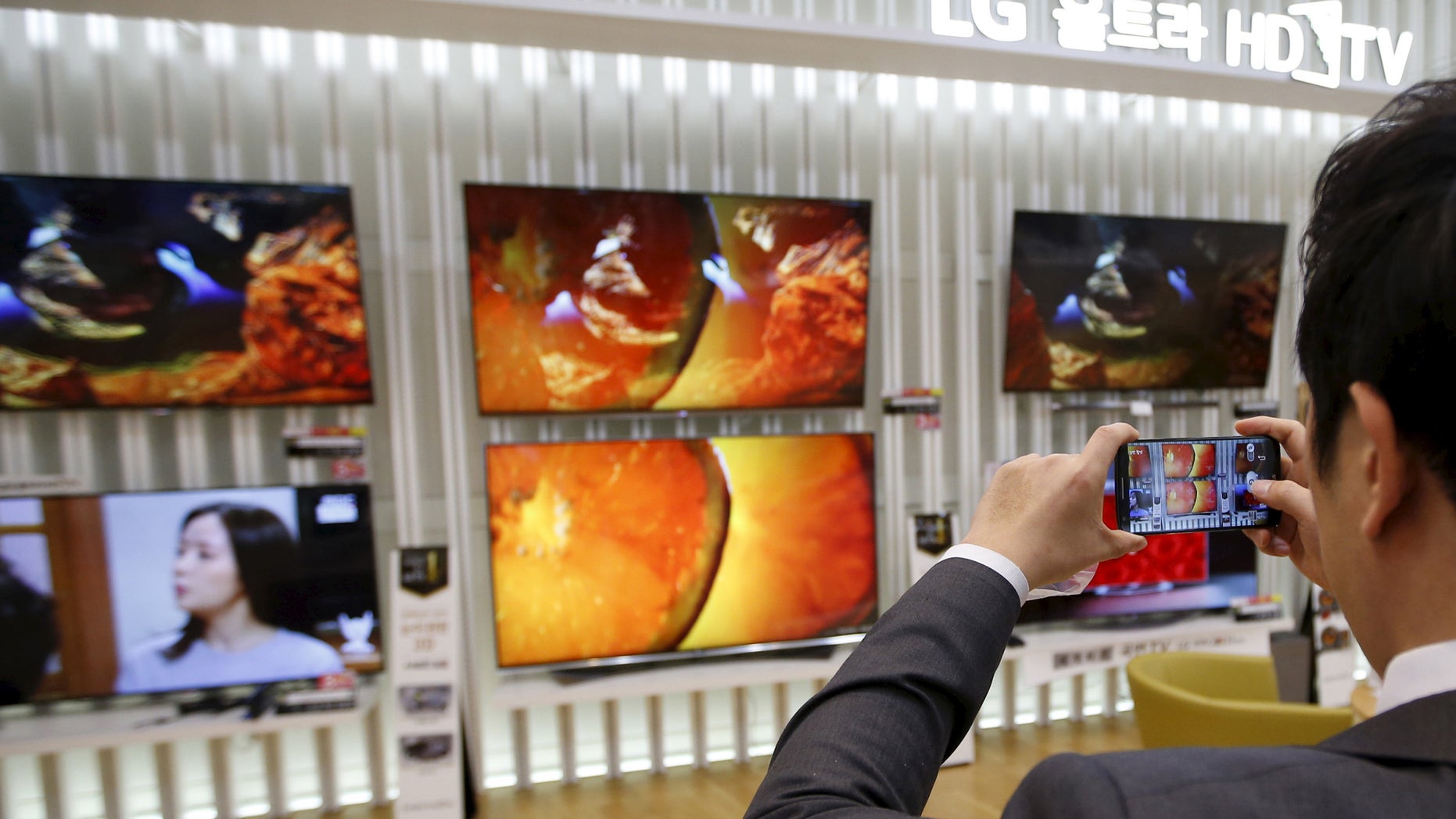 File photo: An employee takes photographs of LG Electronics' organic light-emitting diode (OLED) TV sets, which are made with LG Display flat screens, at its store in Seoul January 28, 2015. (REUTERS/Kim Hong-Ji)