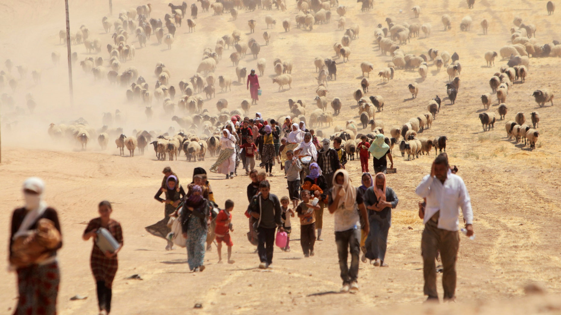 Displaced people from the minority Yazidi sect, fleeing violence from forces loyal to the Islamic State in Sinjar town, walk towards the Syrian border, on the outskirts of Sinjar mountain, near the Syrian border town of Elierbeh of Al-Hasakah Governorate August 10, 2014. REUTERS/Rodi Said/File Photo - RTX2GIYQ
