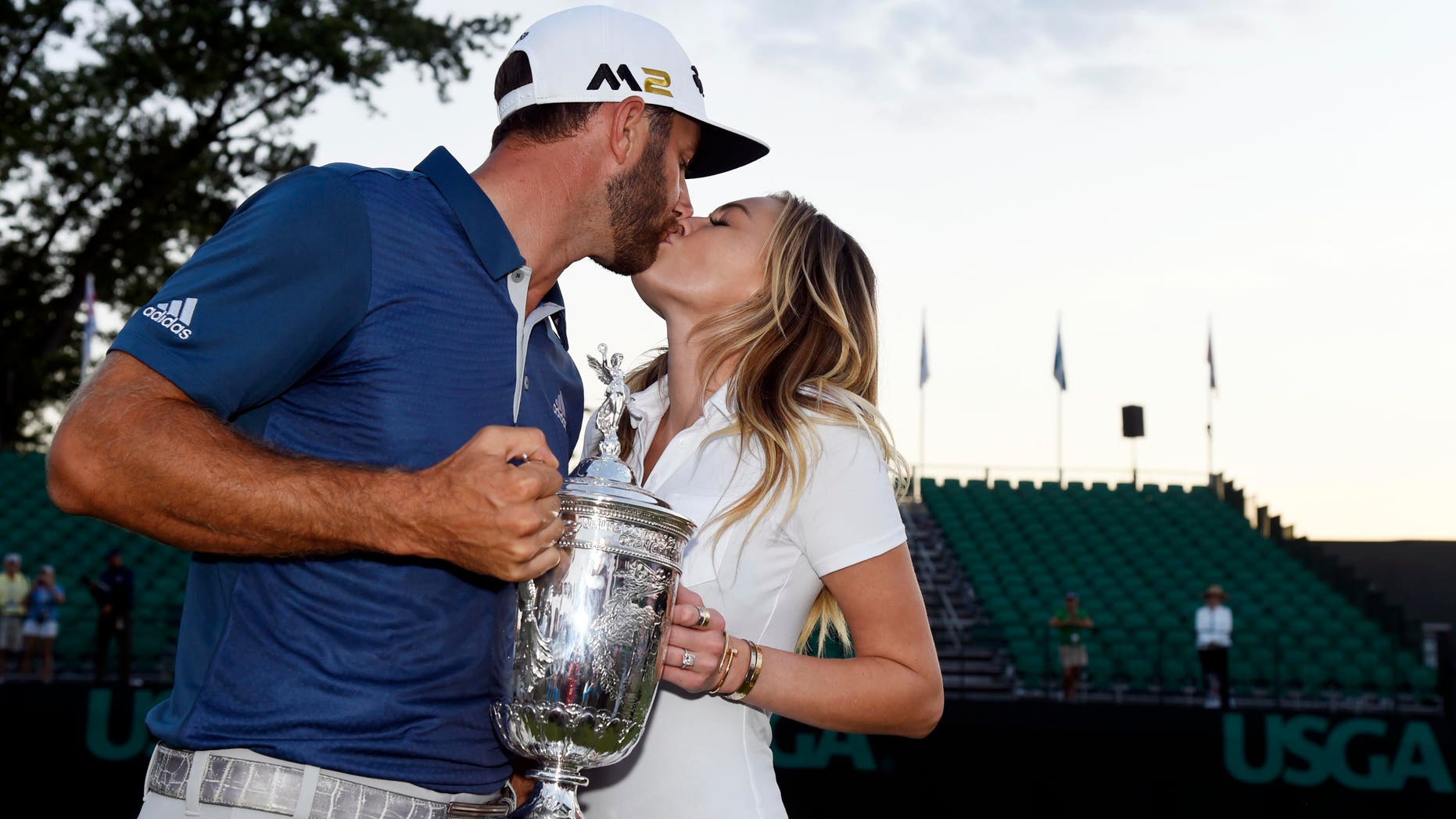 Jun 19, 2016; Oakmont, PA, USA; Dustin Johnson kisses his fiance Paulina Gretzky while holding the championship trophy after winning the U.S. Open golf tournament at Oakmont Country Club.