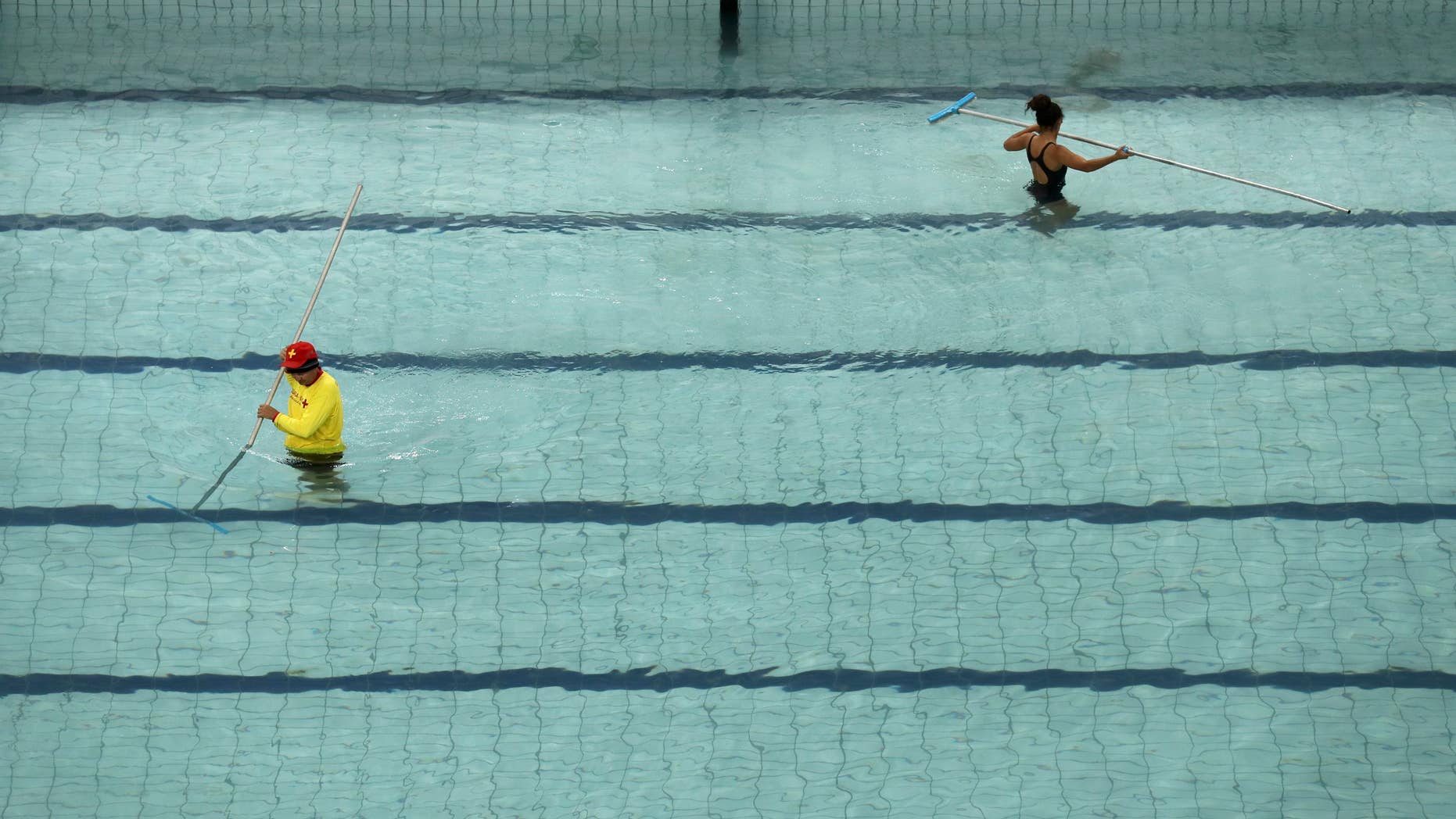 Technicians and lifeguards drain water from the synchronised swimming pool before it is replaced.