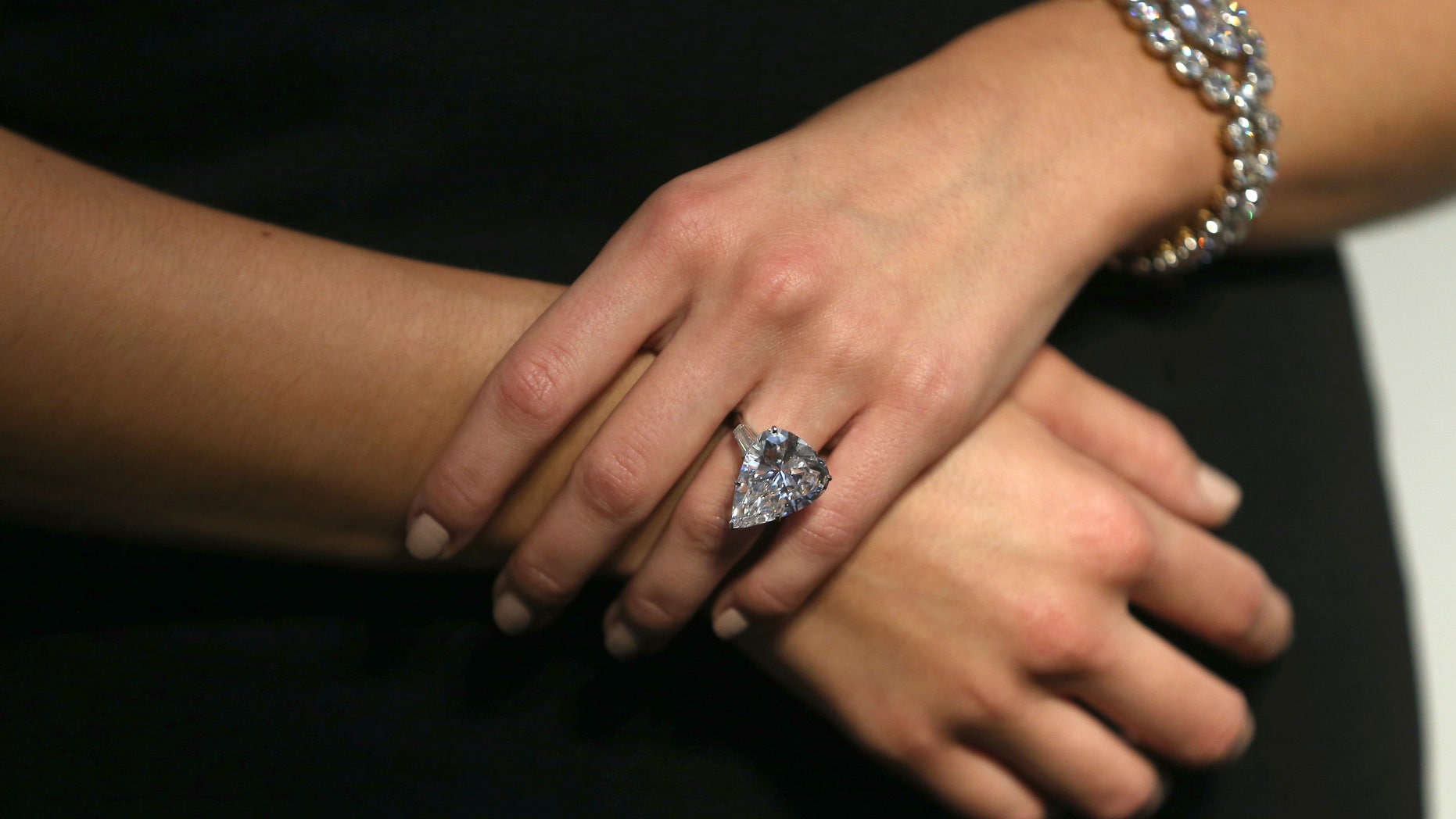 An assistant poses with a Star of Sierra Leone 968.9 carat diamond ring and a 7.13 carat diamond Cartier bracelet, during a sale preview at Christie's auction house in London, Britain October 20, 2016. (REUTERS/Neil Hall)