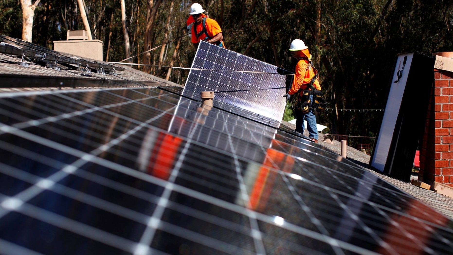 Solar installers from Baker Electric place solar panels on the roof of a residential home in Scripps Ranch, San Diego, Calif., Oct. 14, 2016.