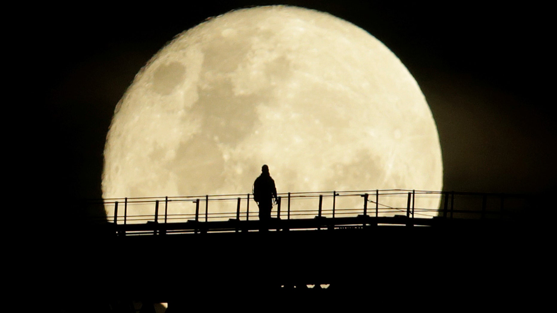 A man walks on the top span of the Sydney Harbour Bridge as the supermoon enters its final phase in Sydney, Australia, November 15, 2016.
