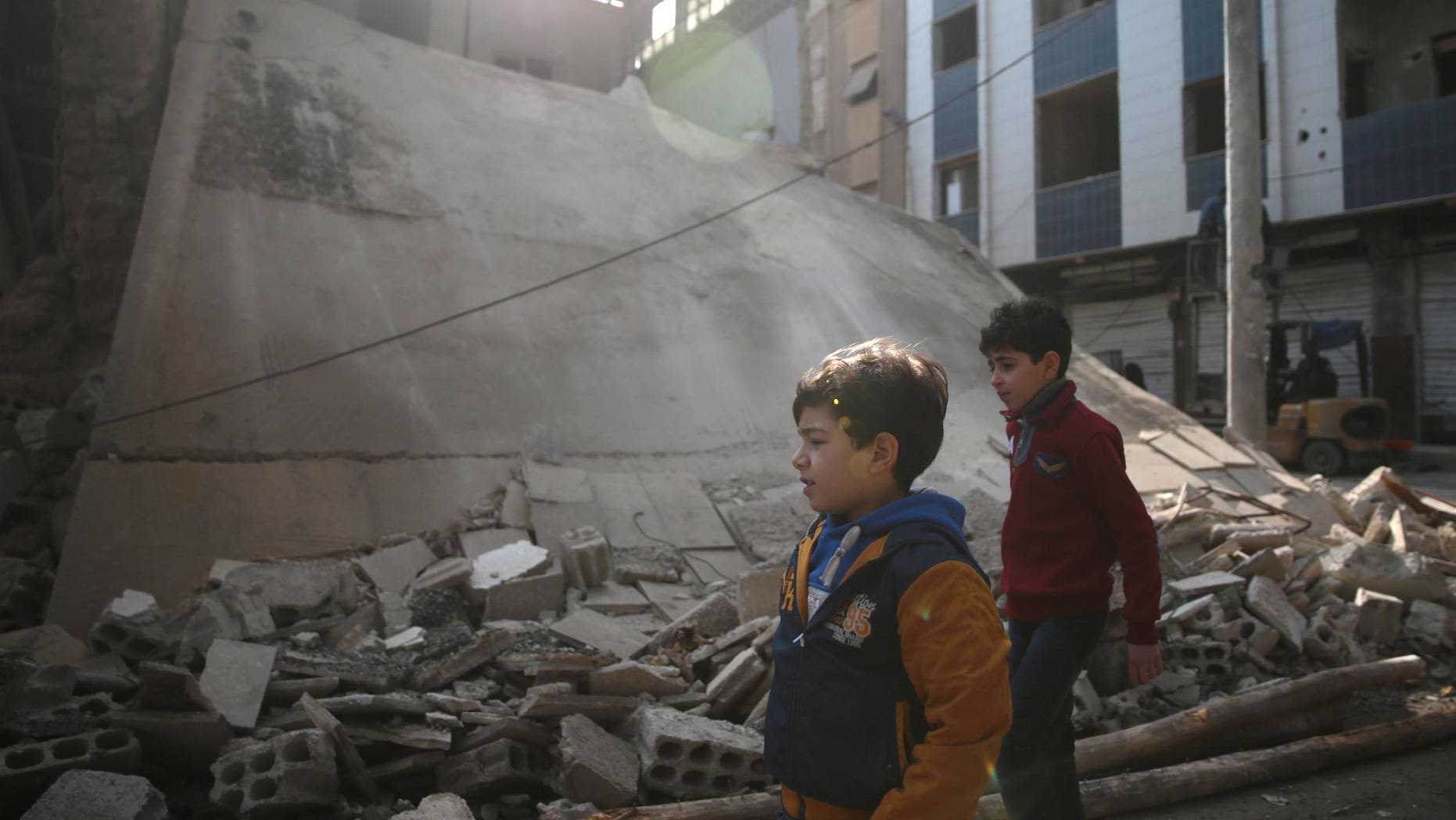 Boys walk near a damaged building in the rebel held besieged city of Douma, in the eastern Damascus suburb of Ghouta, Syria December 30, 2016. REUTERS/Bassam Khabieh - RTX2WYAO