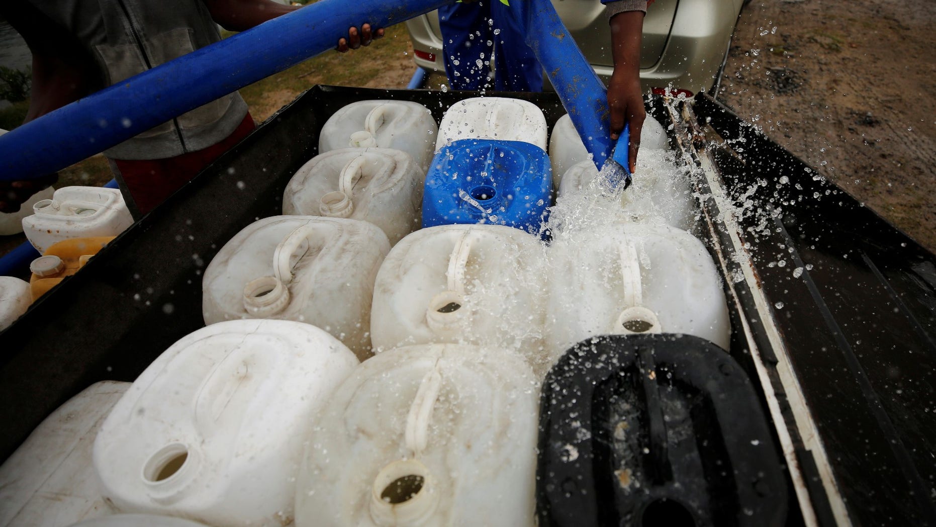 FILE -- Residents fill containers with water from a polluted river in Cape Town, South Africa, February 2, 2018.