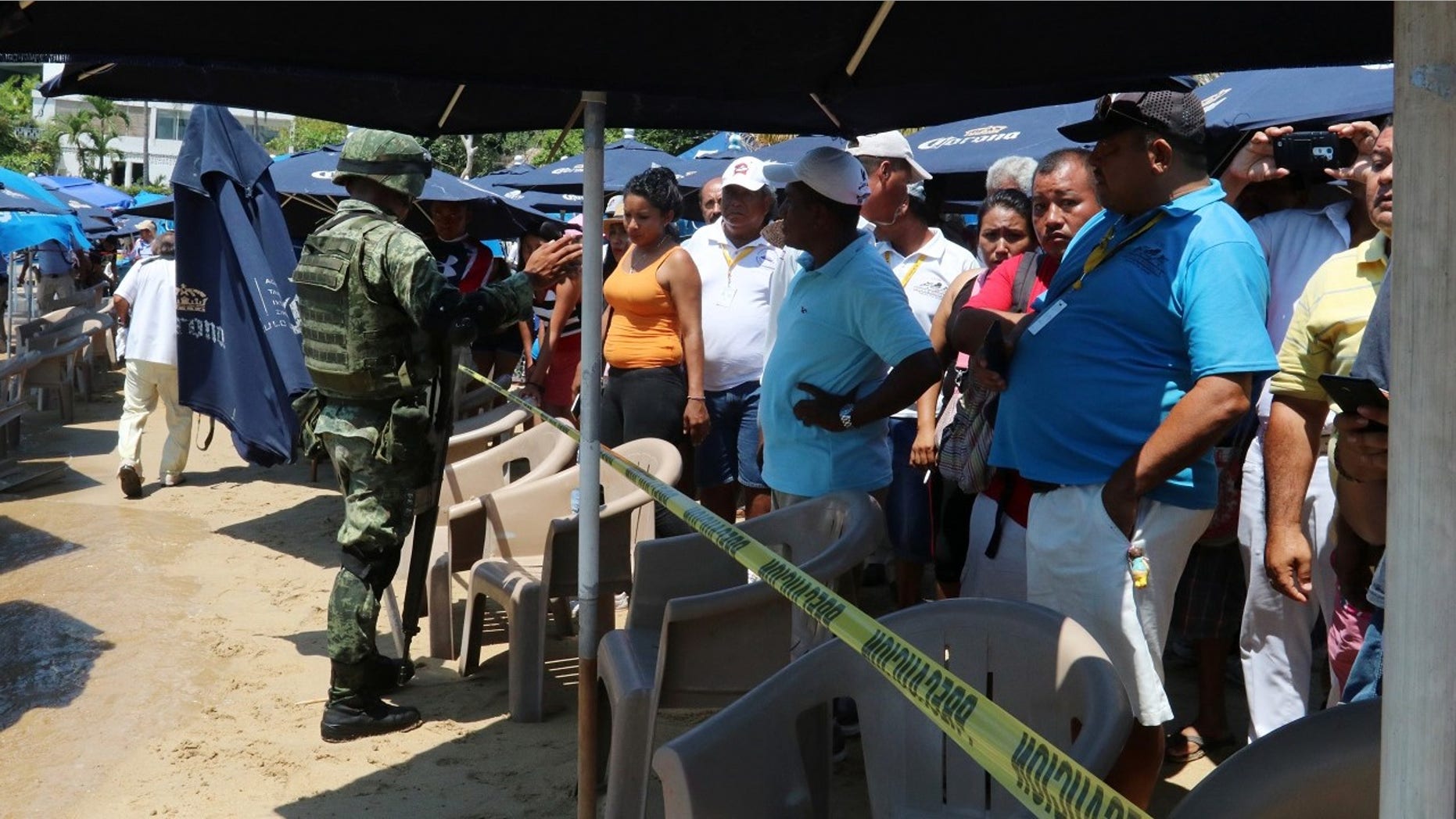 Tourist and residents look at the body of a man who washed ashore near a Mexico tourist destination.
