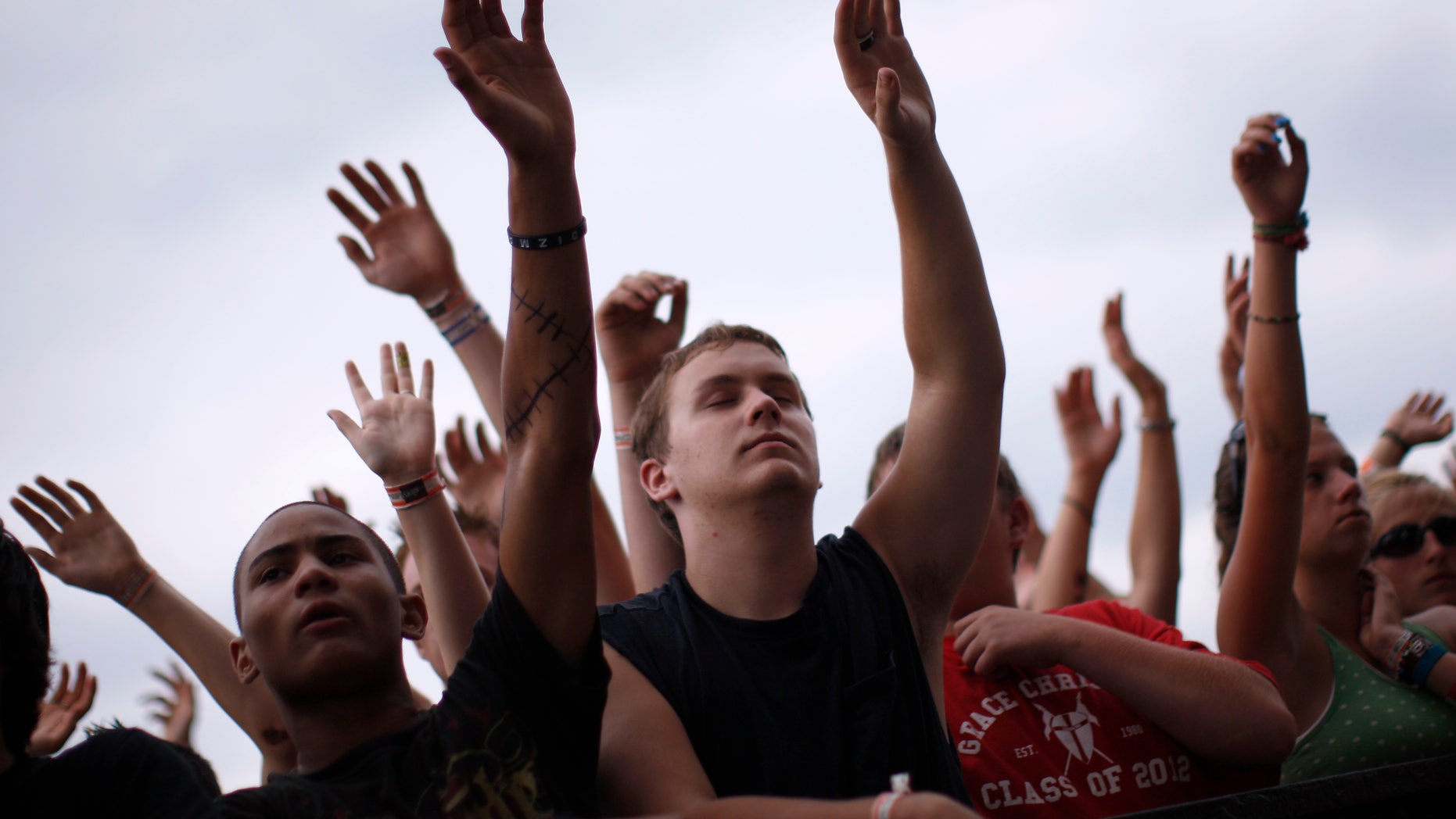 People in the crowd raise their hands together in worship as they listen to the band The Afters at the Creation Christian music festival near Mount Union, Pennsylvania in 2008.