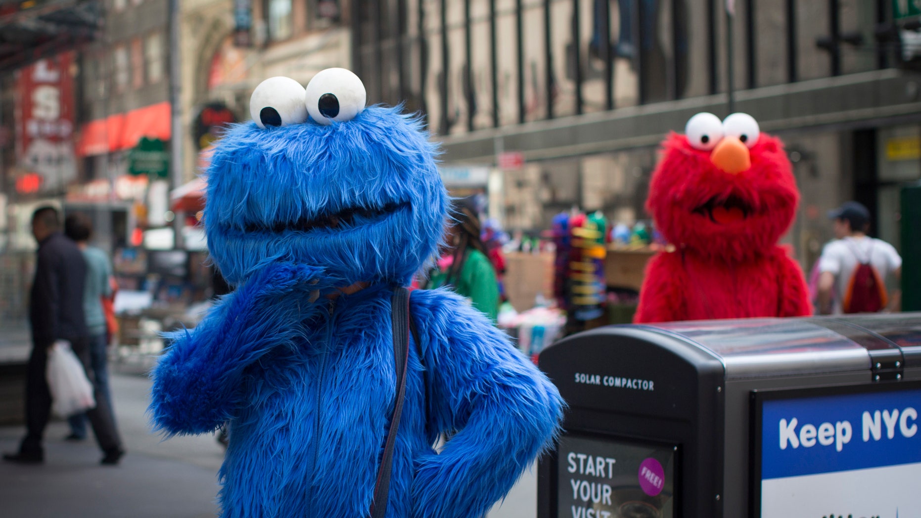 Characters dressed up as the Cookie Monster and Elmo from Sesame Street stand in Times Square while waiting to pose for photographs with people for tips in New York April 9, 2013. REUTERS/Shannon Stapleton (UNITED STATES - Tags: SOCIETY) - RTXYF7F