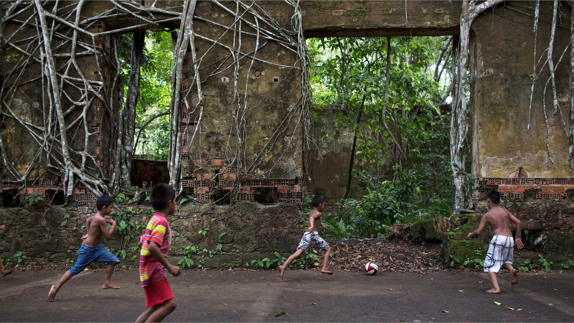In this May 21, 2014 photo, Children play soccer in the ruins of Paricatuba, near Manaus, Brazil.