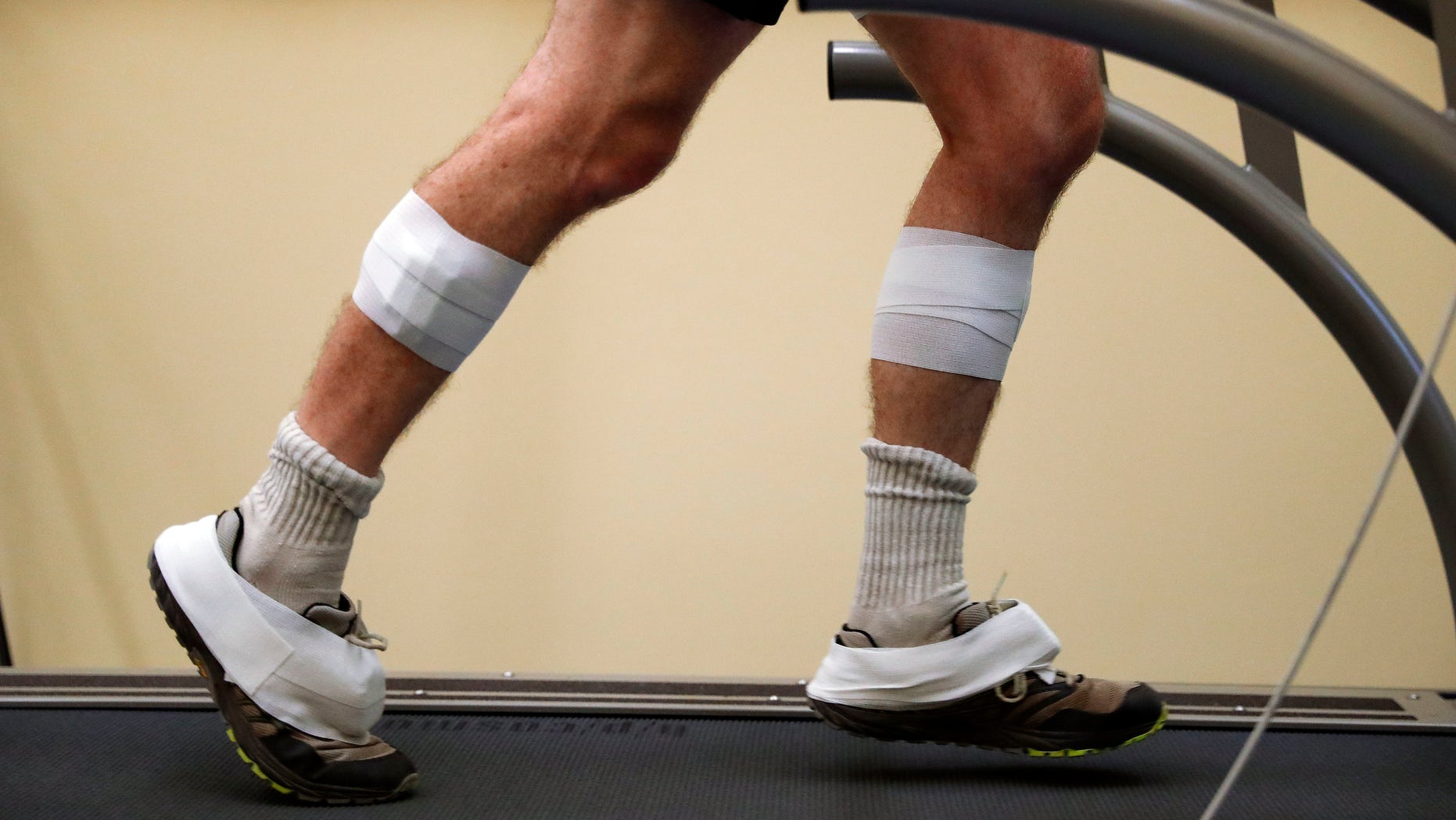 In this Friday, Aug. 12, 2016 photo, sensors are shown taped to the legs and feet of David Moran as he runs on a treadmill in Ann Arbor, Mich