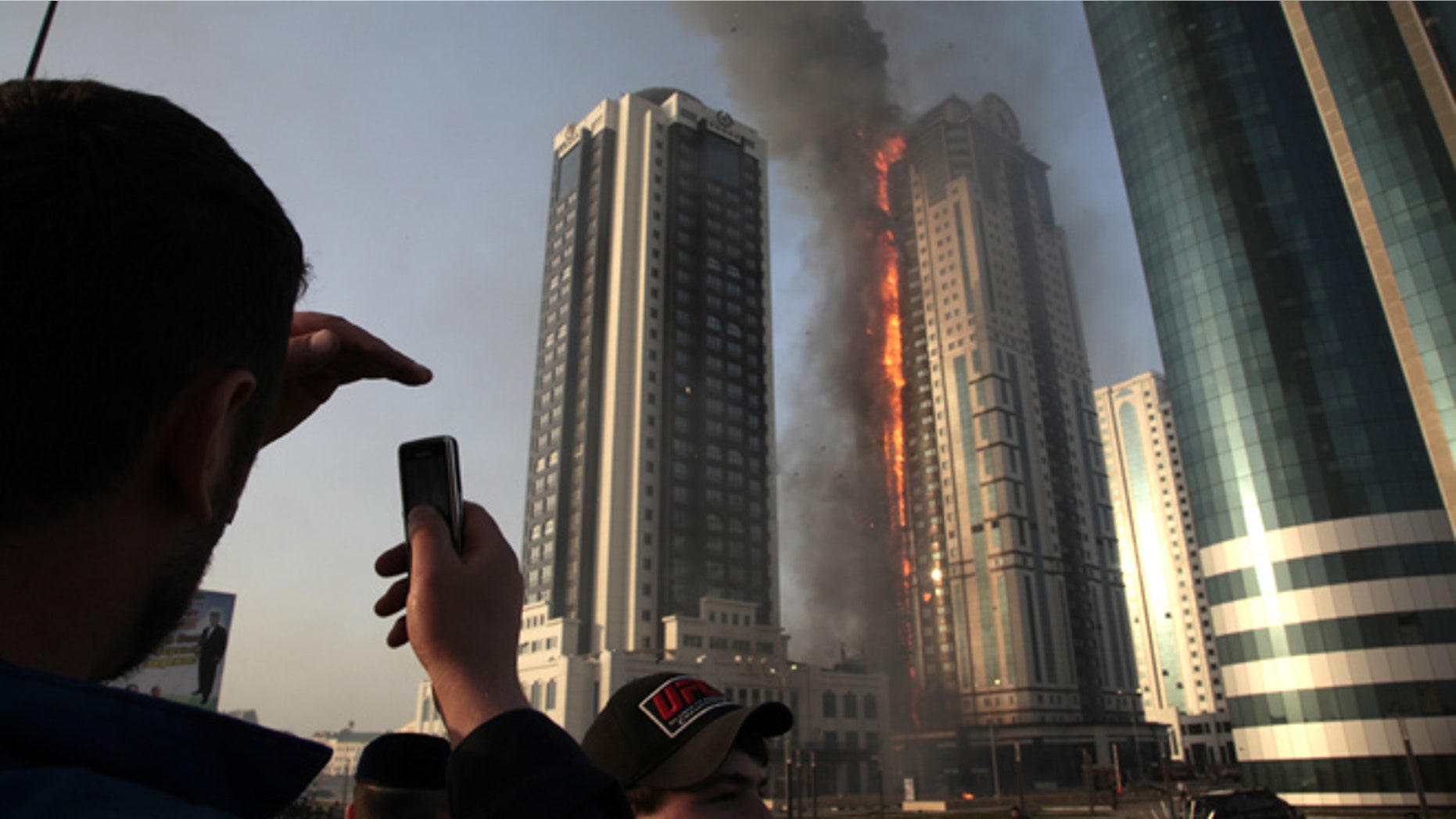 April 3, 2013: A local resident makes photos with a mobile phone of a fire in a high-rise apartment building in provincial capital Grozny, Russia. French actor Gerard Depardieu reportedly received an apartment in the complex of buildings as a gift from Chechen leader Ramzan Kadyrov.