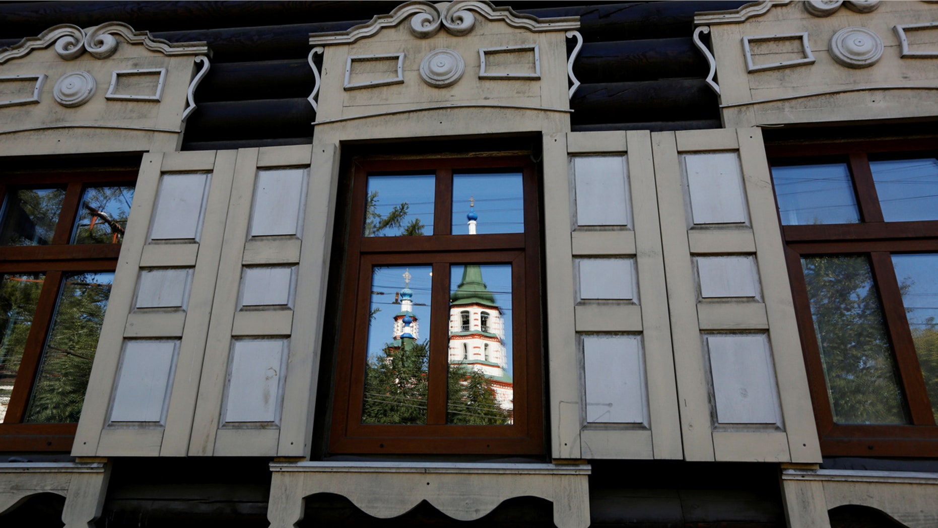 The Feast of the Holy Cross Church is reflected in a window of a 19th century wooden house in the center of the East Siberian city of Irkutsk, Russia, September 8, 2016. REUTERS/Ilya Naymushin - RTSO0O5