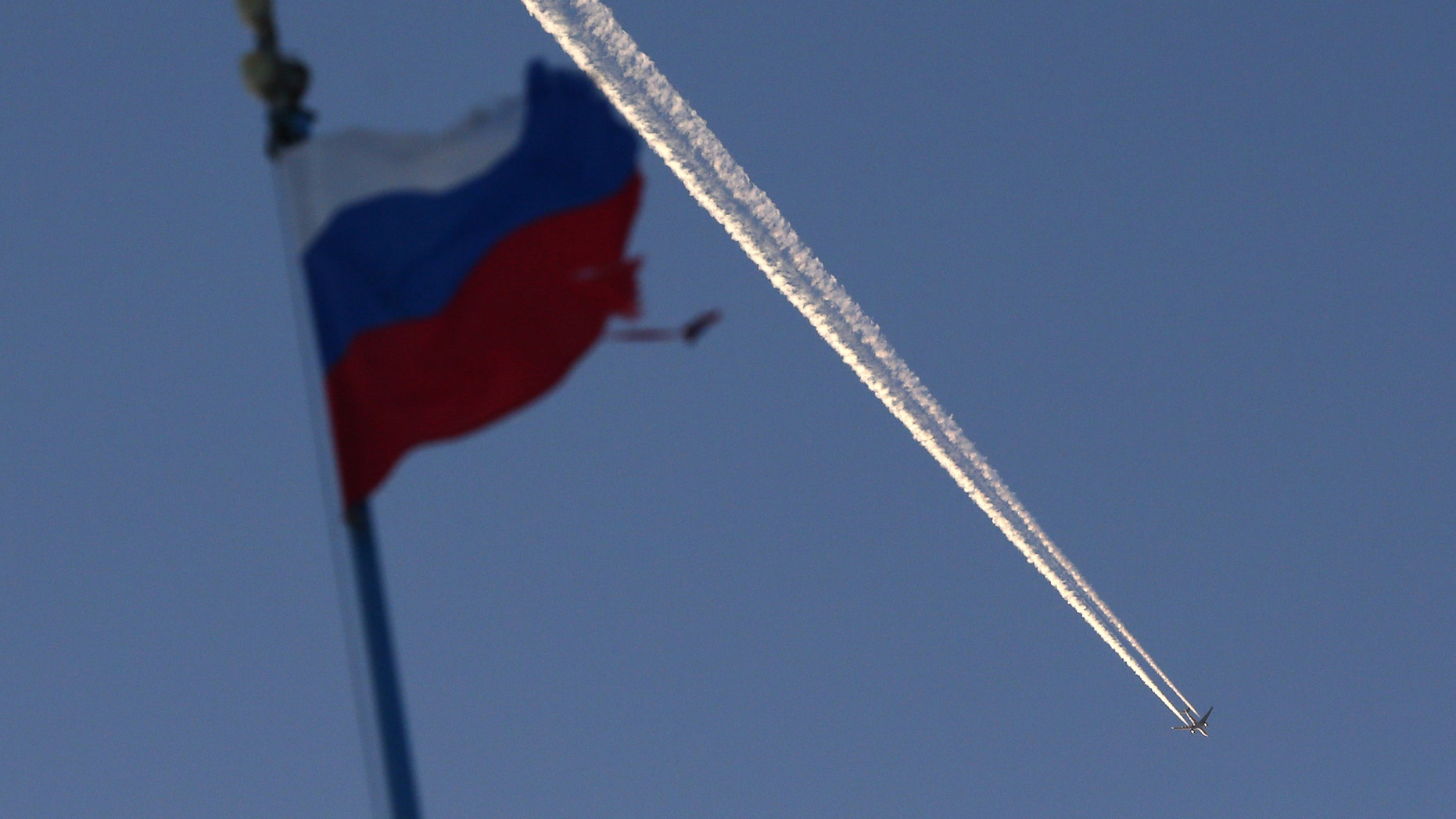 File photo - The Russian state flag flutters, with a plane flying in the sky in the background, outside the Siberian city of Krasnoyarsk, Russia Jan. 27, 2018. (REUTERS/Ilya Naymushin)
