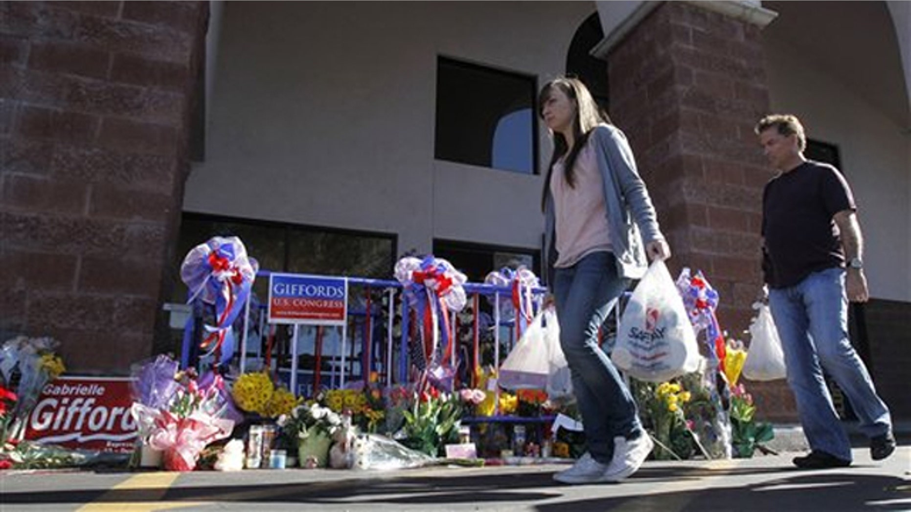 In this Jan. 15 photo, patrons walk past a makeshift memorial at the Safeway grocery store in Tucson where a gunman opened fire Jan. 8.