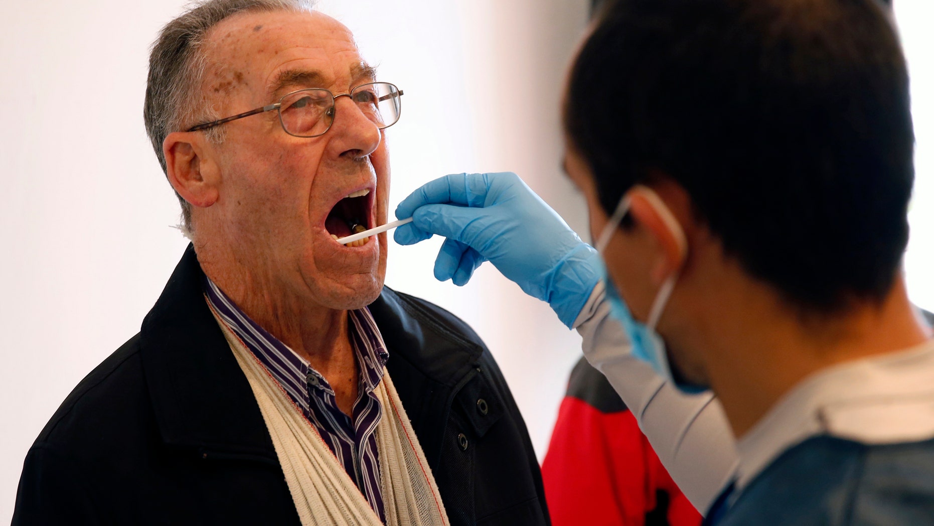 File photo: Gonzalo Carnim, forensic of the Association for the Recovery of Historical Memory (ARMH), takes a saliva sample from a man for a DNA test in Guadalajara's cemetery, Spain, January 22, 2016. (REUTERS/Juan Medina)