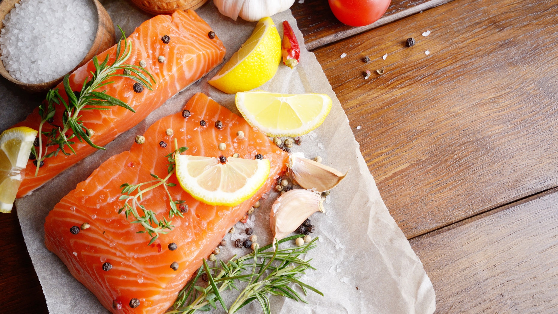 Raw salmon fillet with rosemary pepper sweetbread and salt on baking paper rustic theme with copy-space