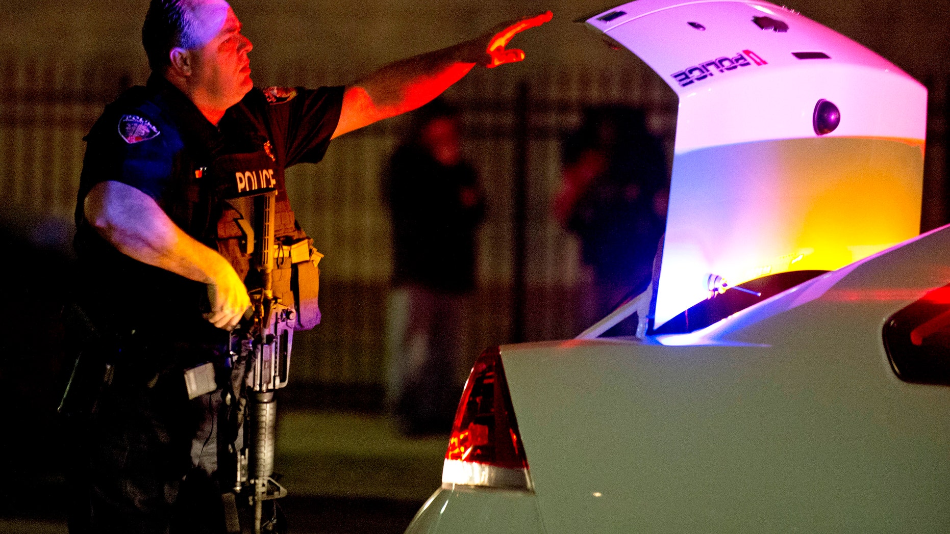 A University of Utah police officer pulls his assault rifle out of the trunk of his squad car as unrest spread throughout Salt Lake City.