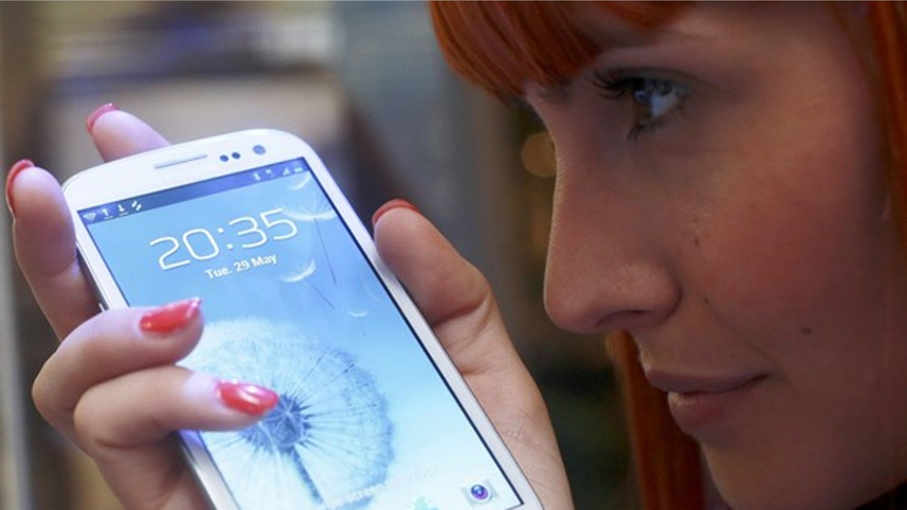 A shop assistant poses with the new Galaxy S III smartphone. Now Samsung wants to get in the social network game.