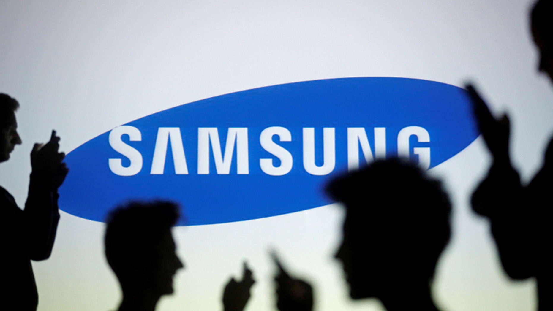 People are silhouetted as they pose with mobile devices in front of a screen projected with a Samsung logo, in this picture illustration taken in Zenica October 29, 2014. (REUTERS/Dado Ruvic/Illustration/File Photo)