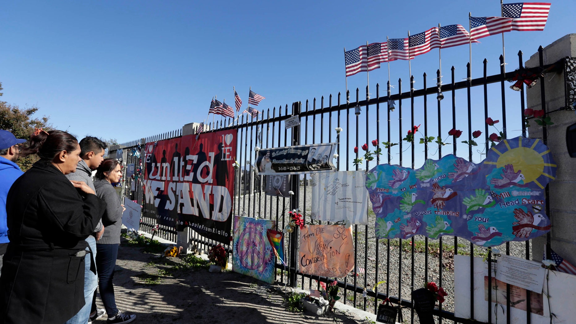 People stand by a make shift memorial for county workers near the Inland Regional Center in San Bernardino, Calif., Friday, Dec. 2, 2016.