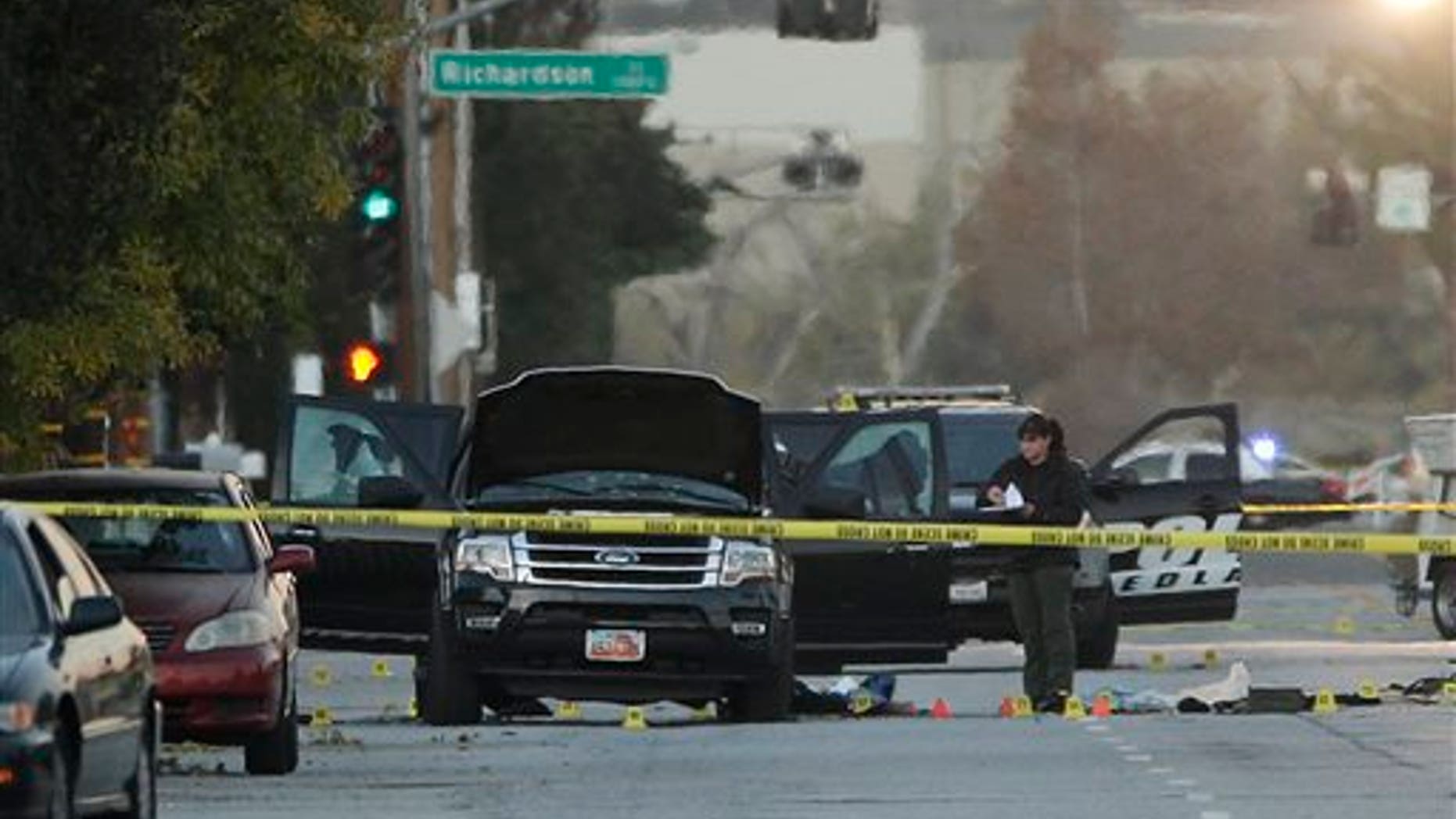 An investigator looks at a Black SUV that was involved in a police shootout with suspects, Thursday, Dec. 3, 2015, in San Bernardino, Calif. A heavily armed man and woman opened fire Wednesday on a holiday banquet, killing multiple people and seriously wounding others in a precision assault, authorities said. Hours later, they died in a shootout with police. (AP Photo/Jae C. Hong)