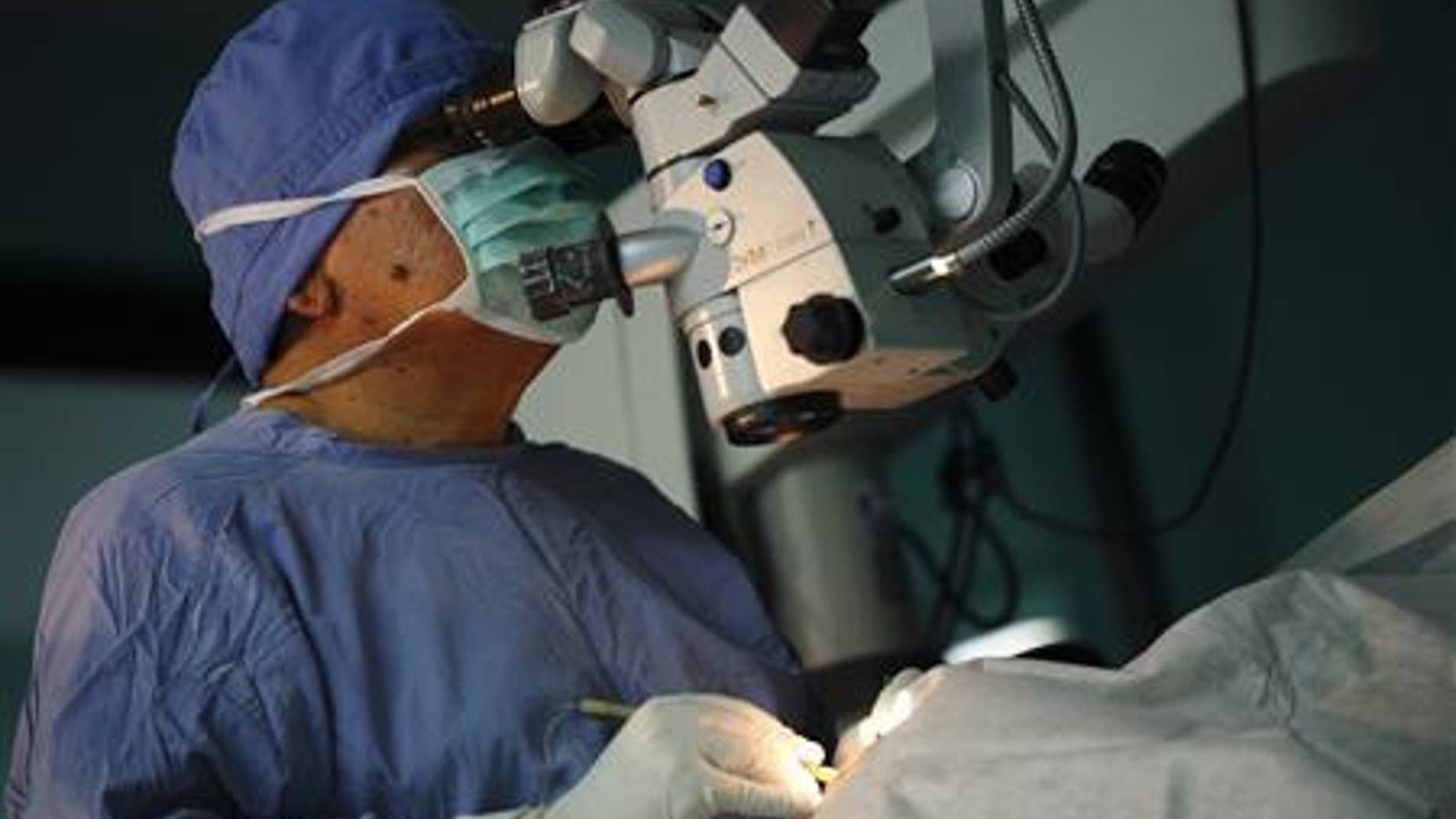 Surgeon Sanduk Ruit looks into the eyes of a patient through a microscope while conducting an operation to remove cataracts at the Tilganga Eye Center in Kathmandu April 25, 2012. A simple eye operation pioneered by Ruit, a Nepali national, at the Tilganga Eye Centre has benefited tens of thousands of people in Nepal and other countries in Asia and Africa, where surgical teams from the centre provide much needed care in field camps. Picture taken April 25, 2012. REUTERS/Navesh Chitrakar
