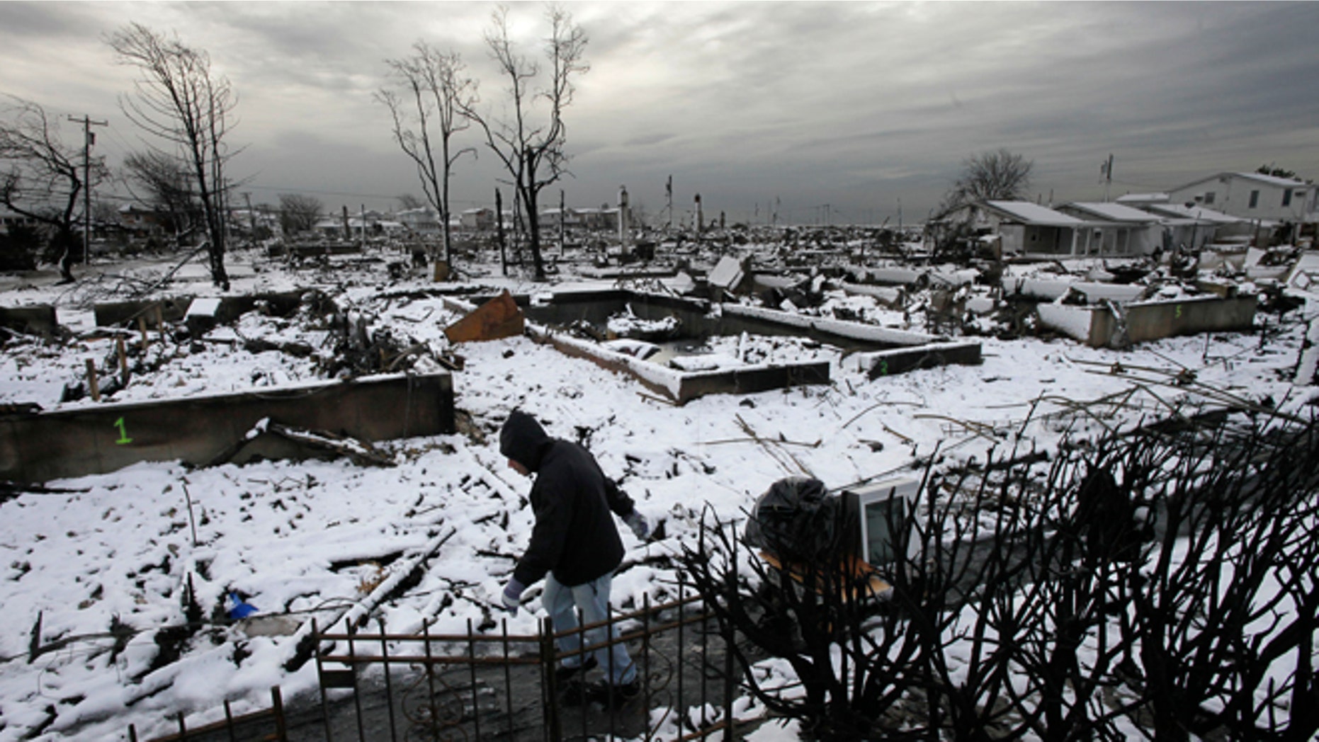 Nov. 8, 2012: Damon Rasinya carts debris from his family home past the fire-scorched landscape of Breezy Point after a Nor'easter snow in New York.