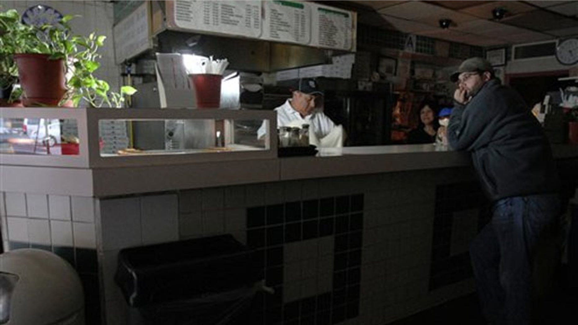 Oct. 31, 2012: Leigh Dworkin, right, waits for a slice of pizza as Carlos Quizhplema, left, and Rosa Rosas work behind the counter at Frank's Trattoria, in New York.